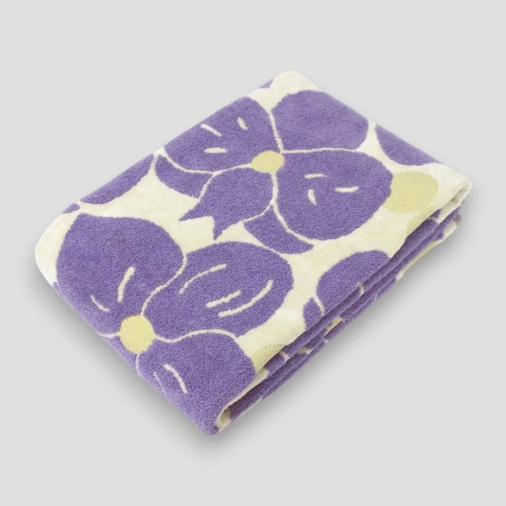 Folded Imabari towels with a jacquard weave featuring a purple phalaenopsis orchid motif