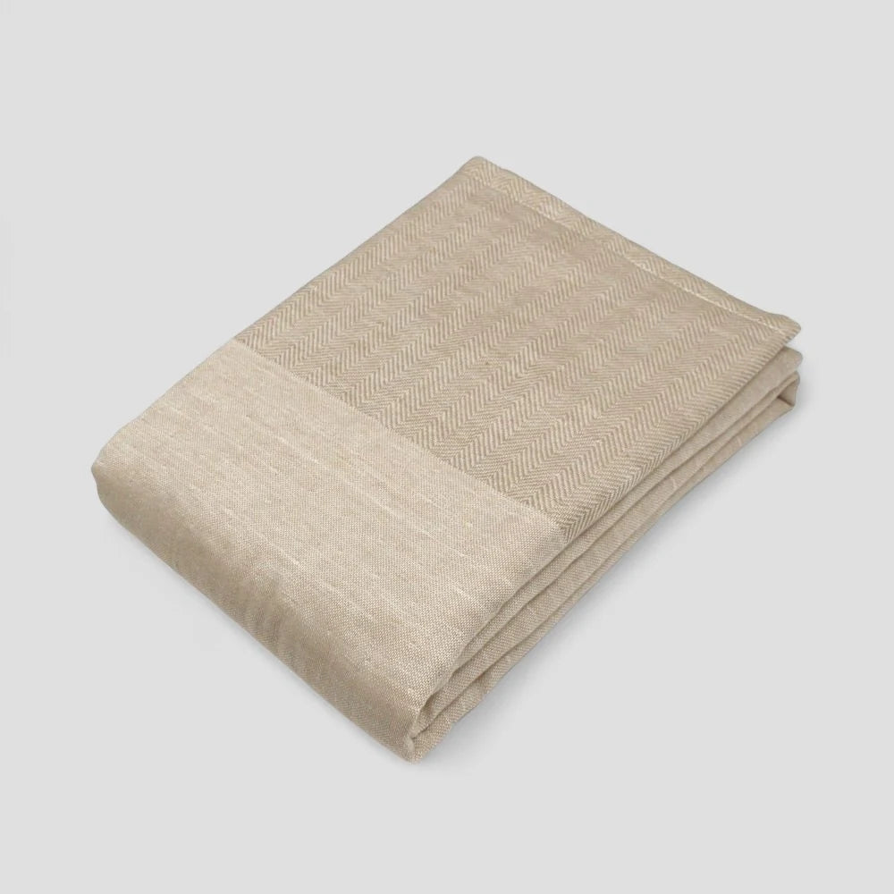 Folded beige Imabari towel with a subtle herringbone pattern on a light gray background.