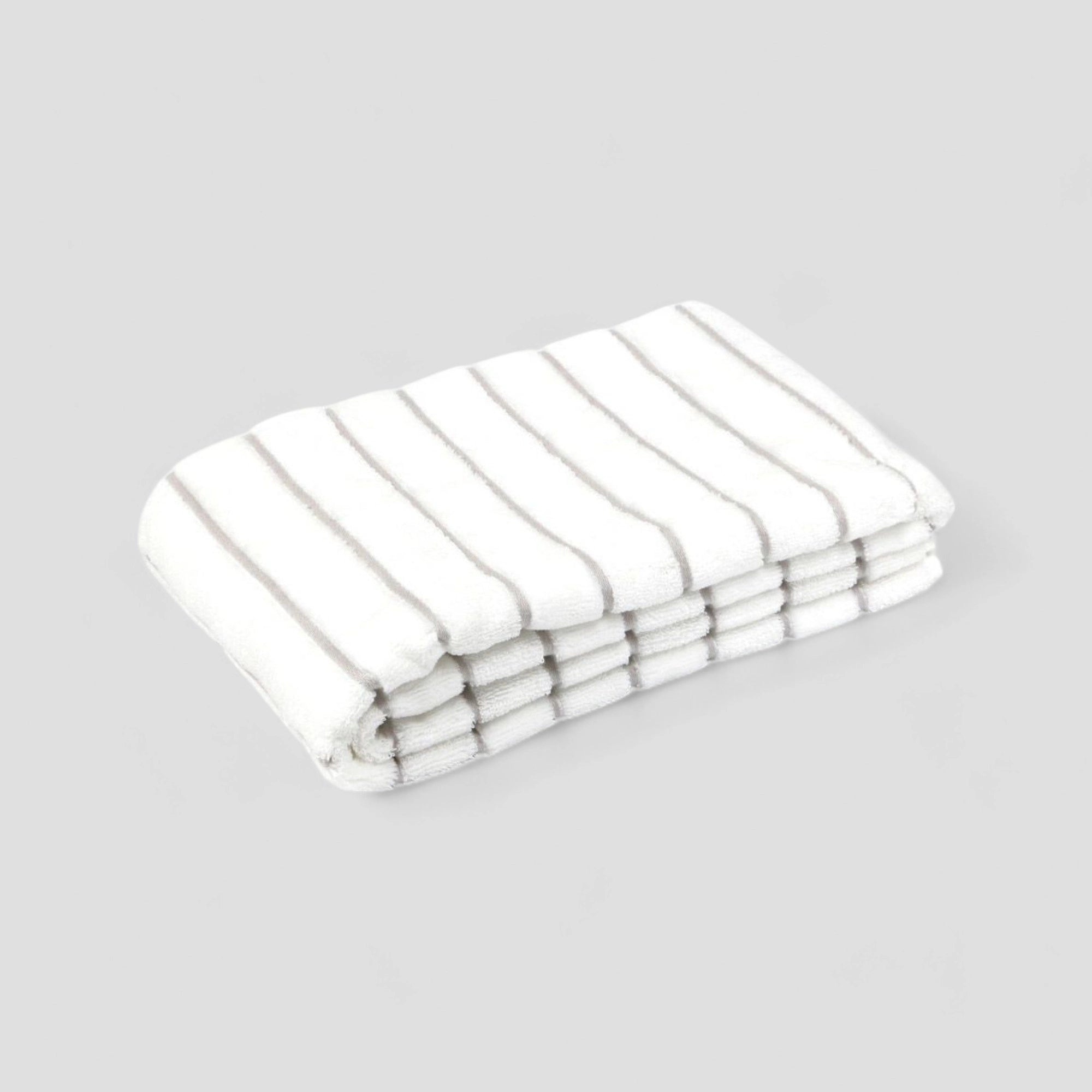 Folded white Imabari towel with gray stripe on the gray background