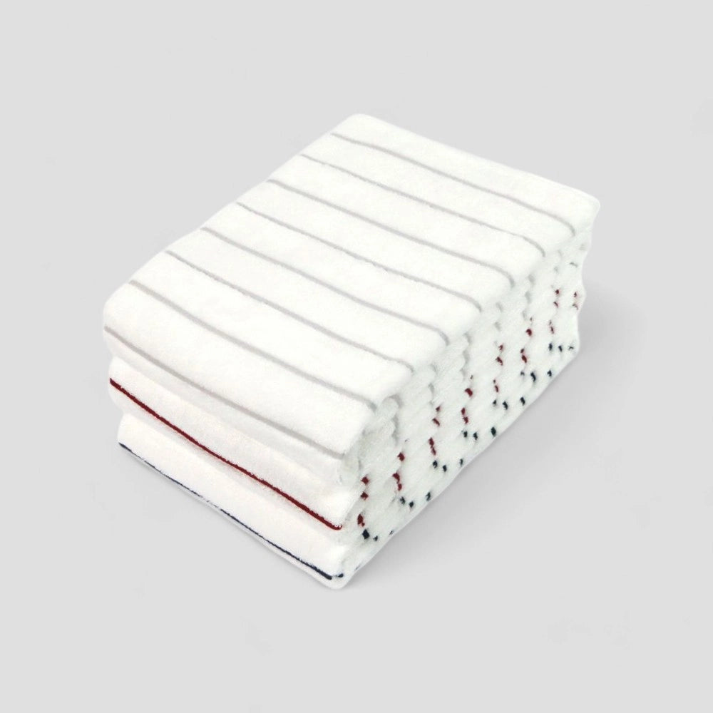 A stack of folded white Imabari bath towels with red, gray and navy stripes on gray background