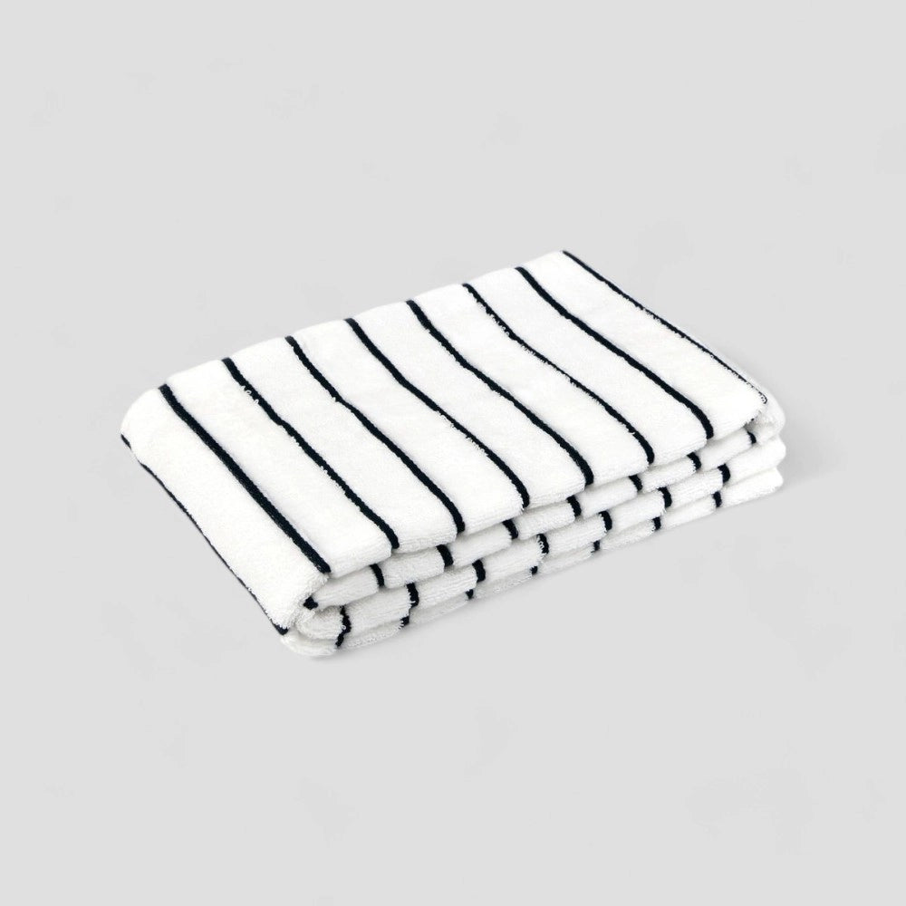 Folded white Imabari towel with navy stripe on the gray background