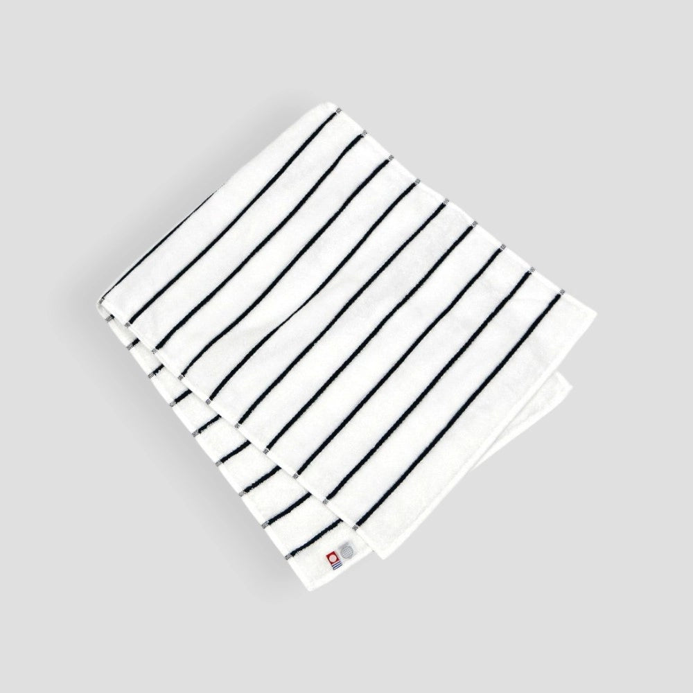 Folded white Imabari towel with navy stripe showing label