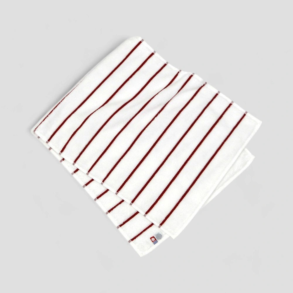 Folded white Imabari towel with red stripe showing label
