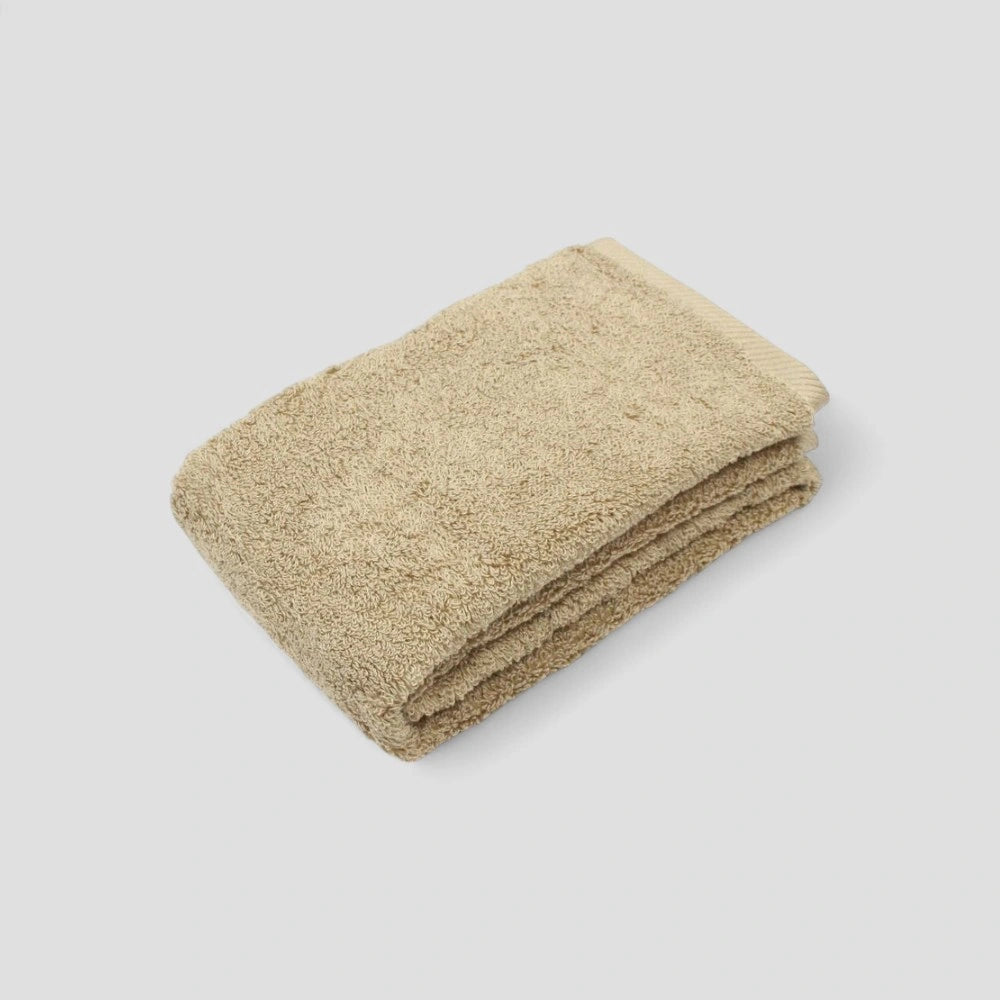 Folded beige Imabari towel on gray background