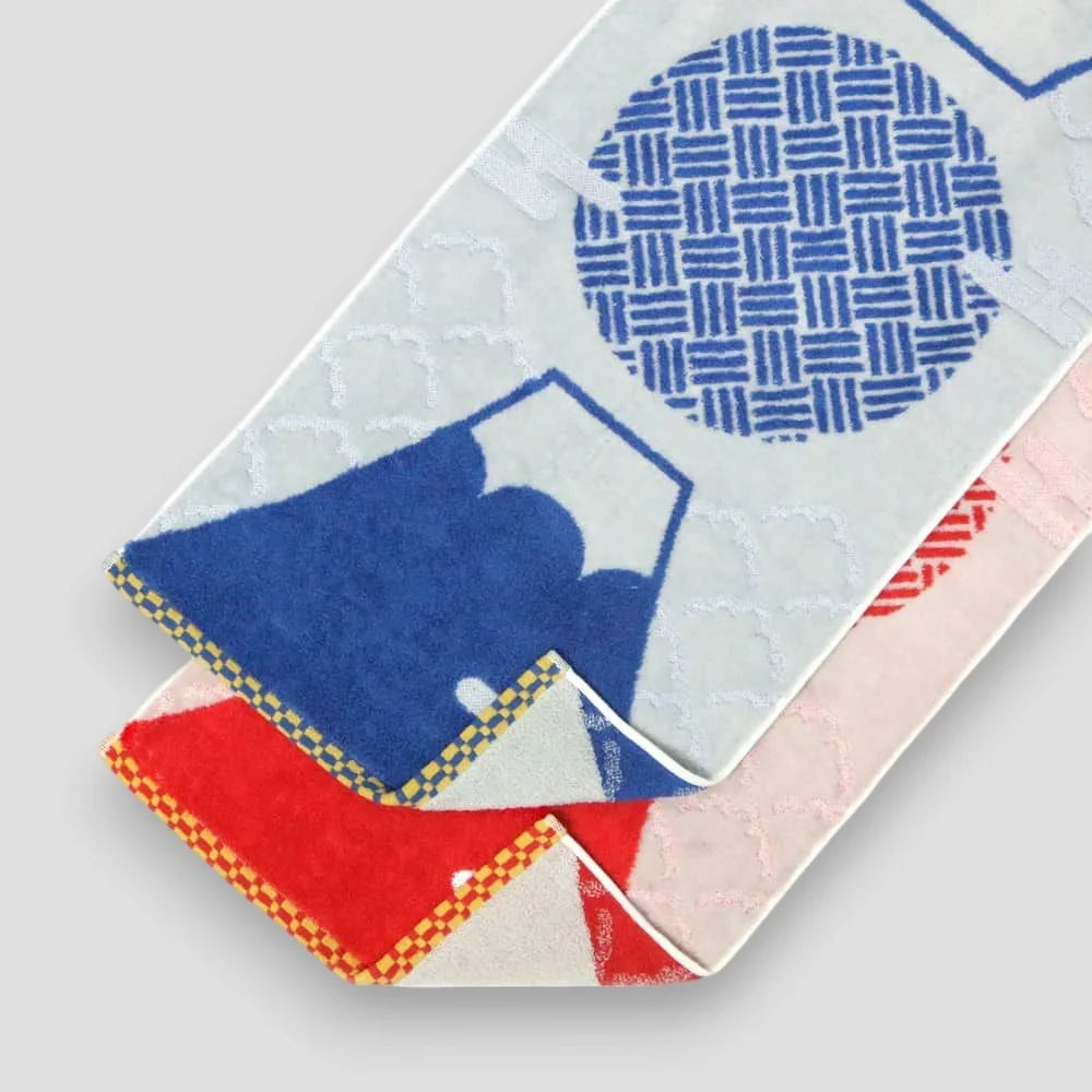 A set of folded Imabari towels featuring geometric patterns and Mt. fuji, with blue and red colors prominently displayed, on a white background.