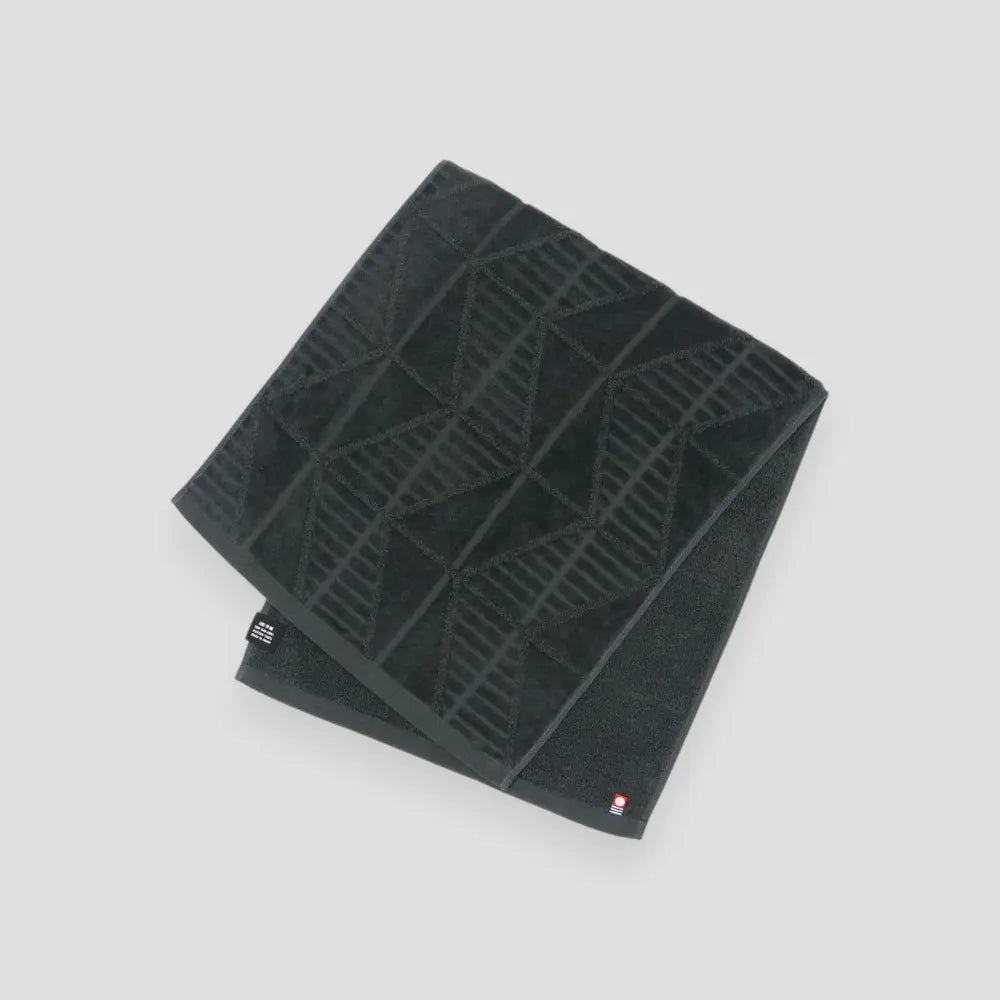 A charcoal Imabati towel with a brand label on a light gray background