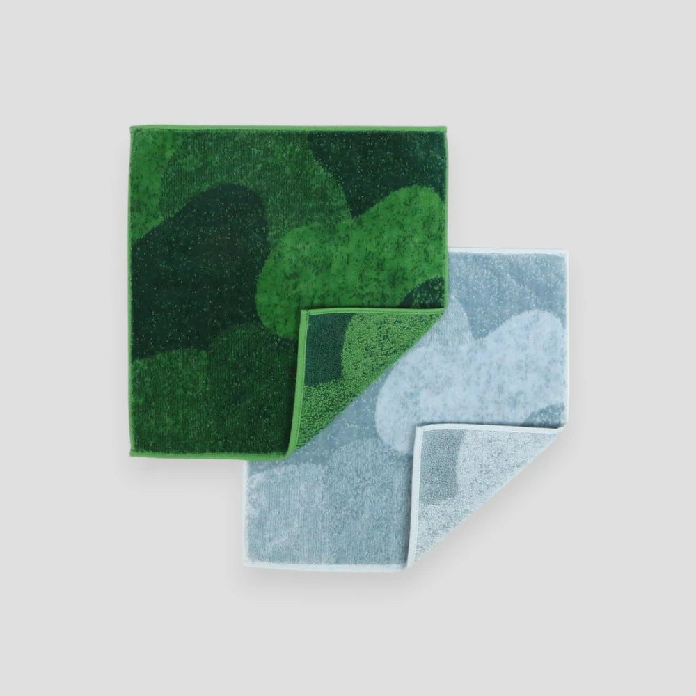 Two mini Imabari towels, one in green resembling moss and the other in gray resembling stone, laid out flat.