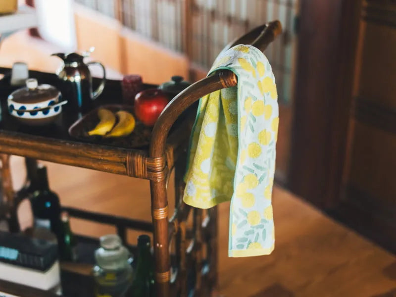 A white Imabari towel with yellow floral pattern hang the wooden bar