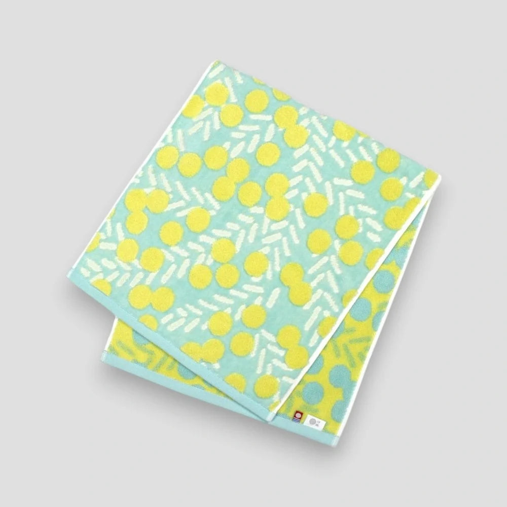 A blue Imabari towel with yellow floral pattern showing tha labels of Imabari towel brand mark and IORI&
