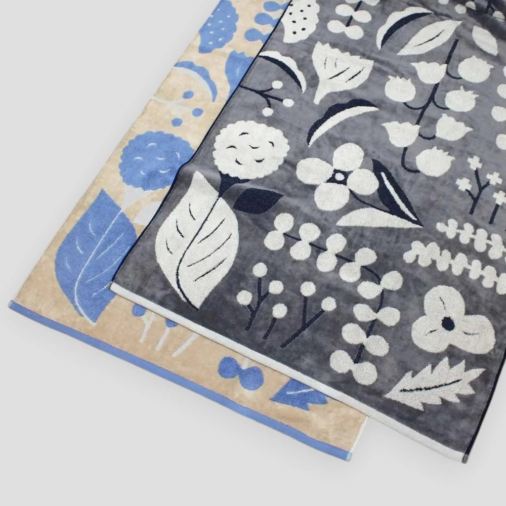 A set of neatly stacked Imabari towels with a floral jacquard pattern in gray and beige colors.