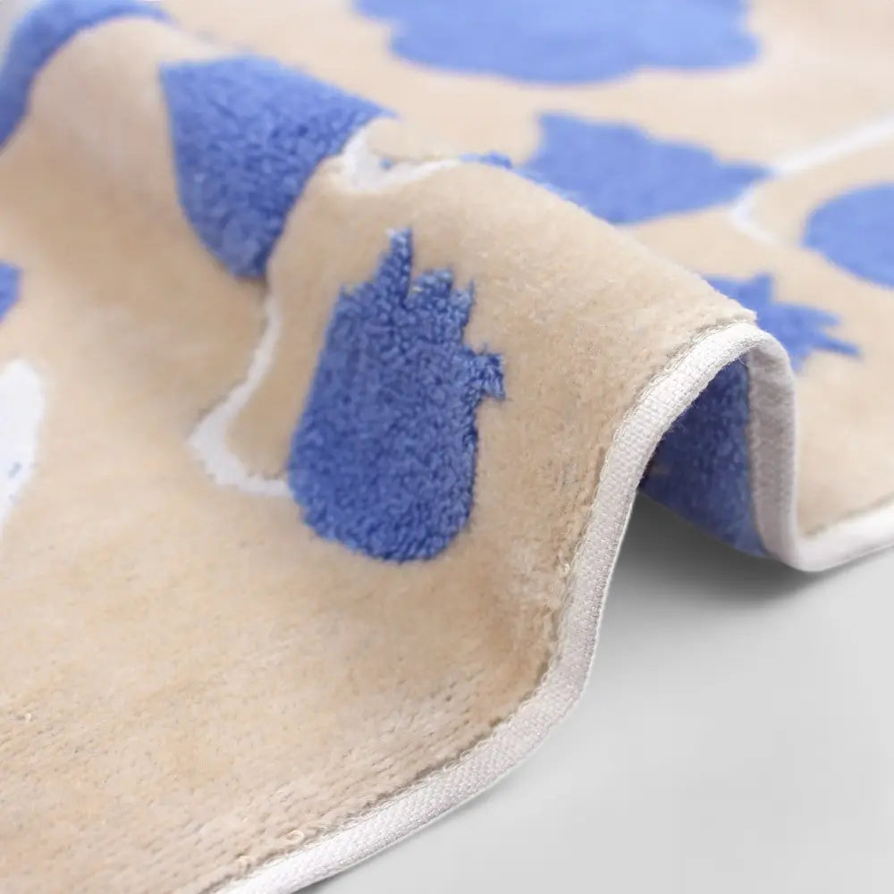 Close up of a side of beige Imabari towel with a jacquard blue floral pattern