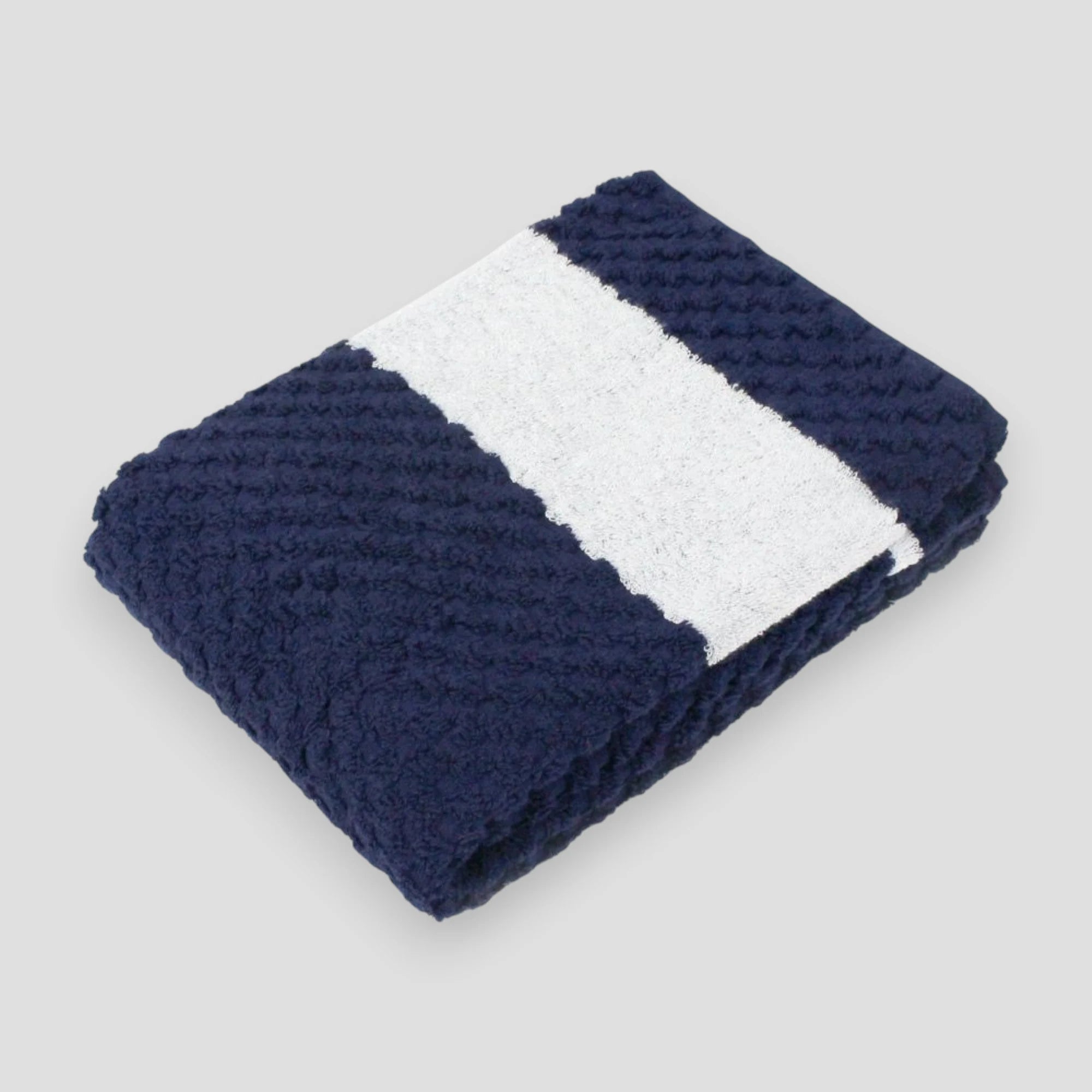 A folded navy jacquard weave towel with a textured design, made of cotton, displayed against a neutral background.