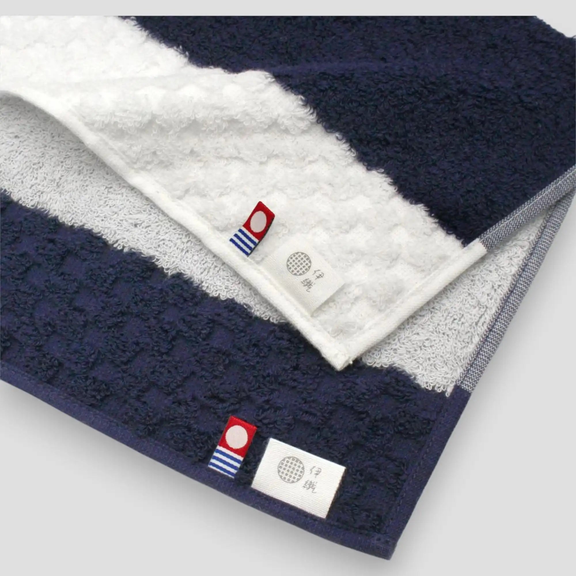 Close-up of Imabari towel branded fabric tags on two colored fabrics.