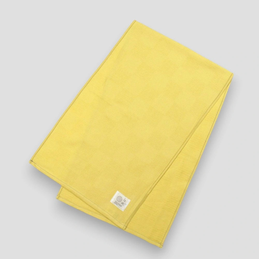 Yellow "Non-Pile" Imabari towel with a brand label on a light gray background