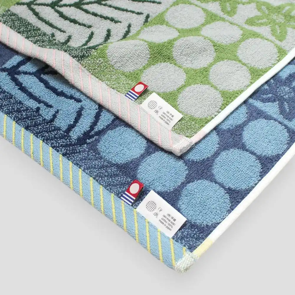 Close-up of green and blue patterned Imabari towel with labels of Imabari towel brand mark and IORI&
