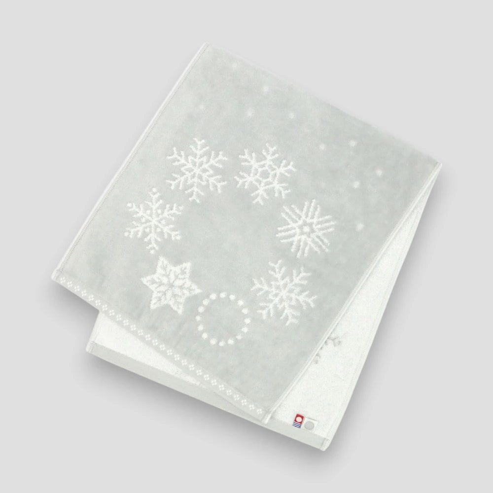 Folded light gray towel with snowflake patterns on a light gray background