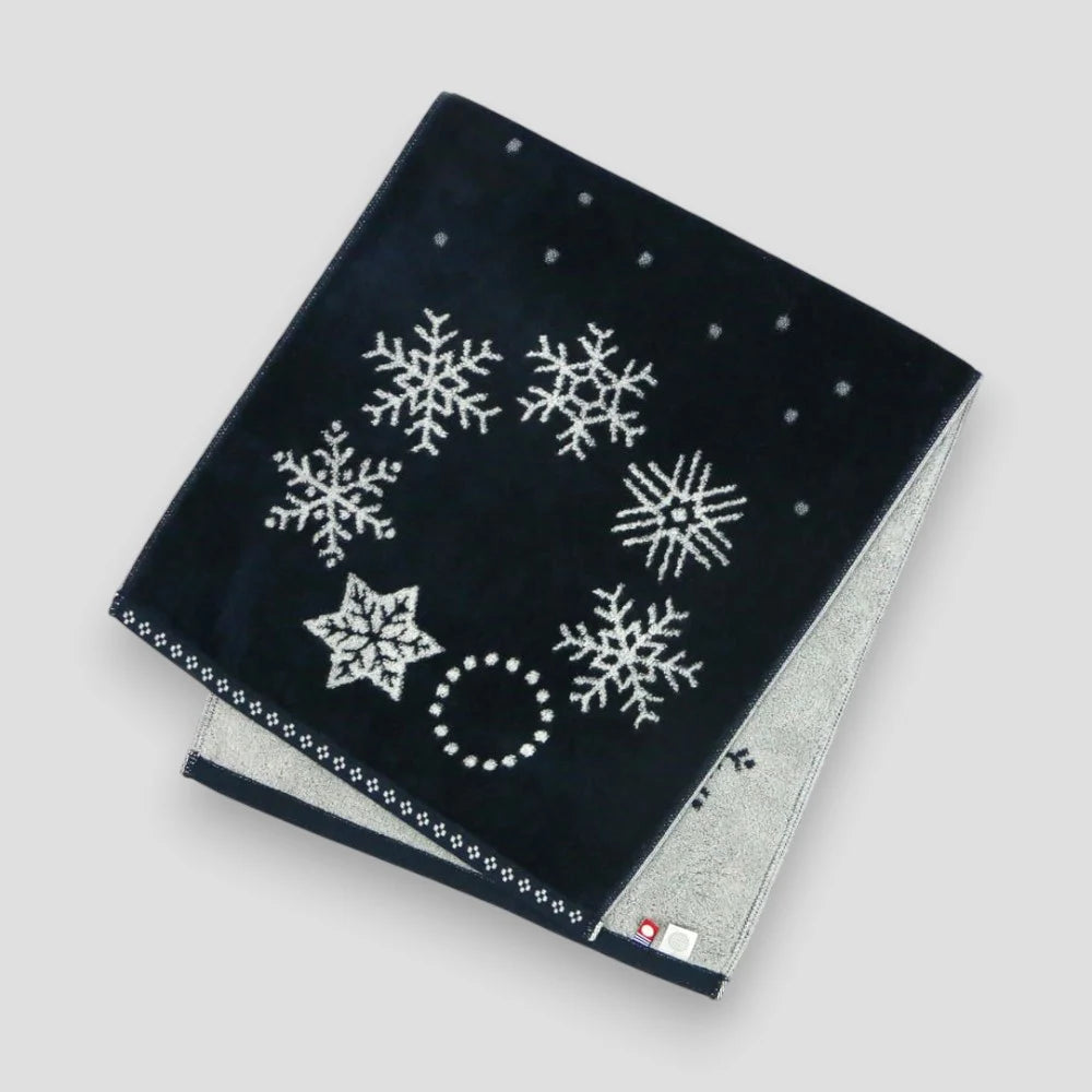 Folded navy Imabari towel with snowflake patterns on a light gray background