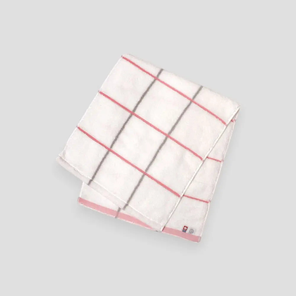 Folded white Imabari towel with pink stripes on a light gray background