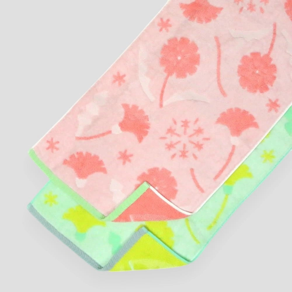 A stack of folded Imabari towels in yellow and pink with floral patterns, made from cotton, on a white background.