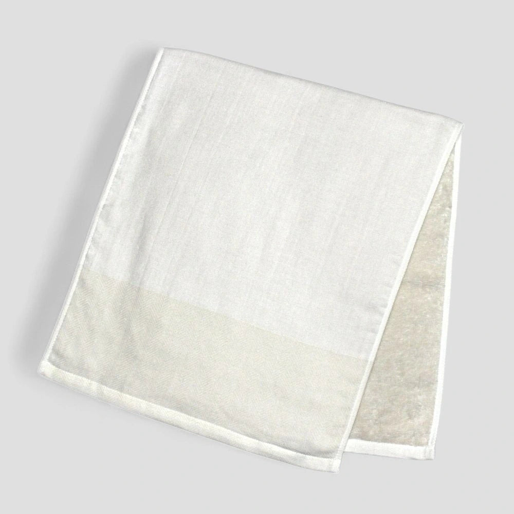 Folded white Imabari towel with a subtle herringbone pattern on a light gray background.