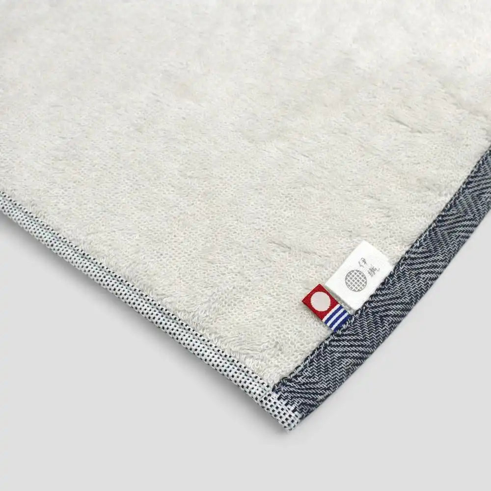 Close-up of a navy Imabari towel with label on a plush pile side.