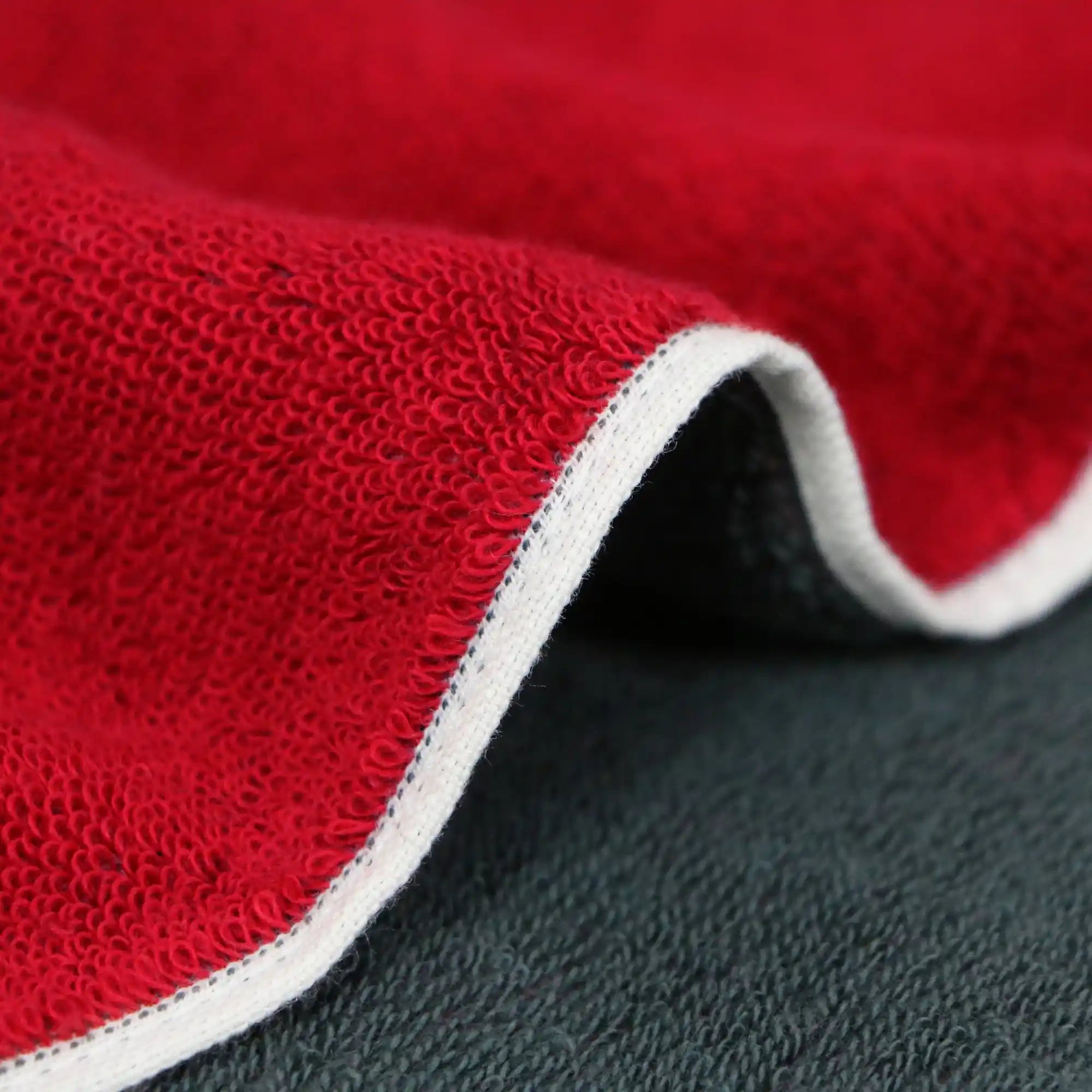 A close-up of the texture and side of a reversible red and gray Imabari towel