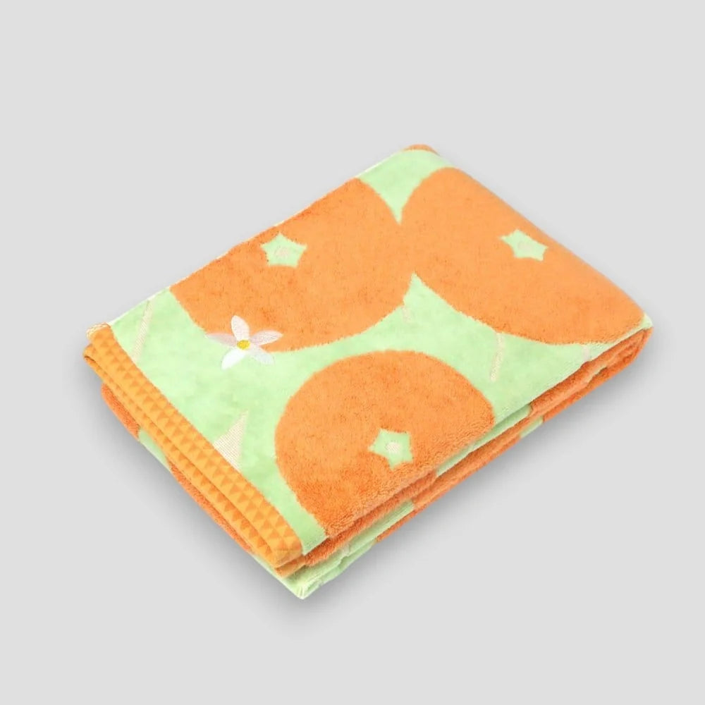 Folded orange Imabari towel featuring a pattern with the Iyokan citrus fruit and green leaves on a white background