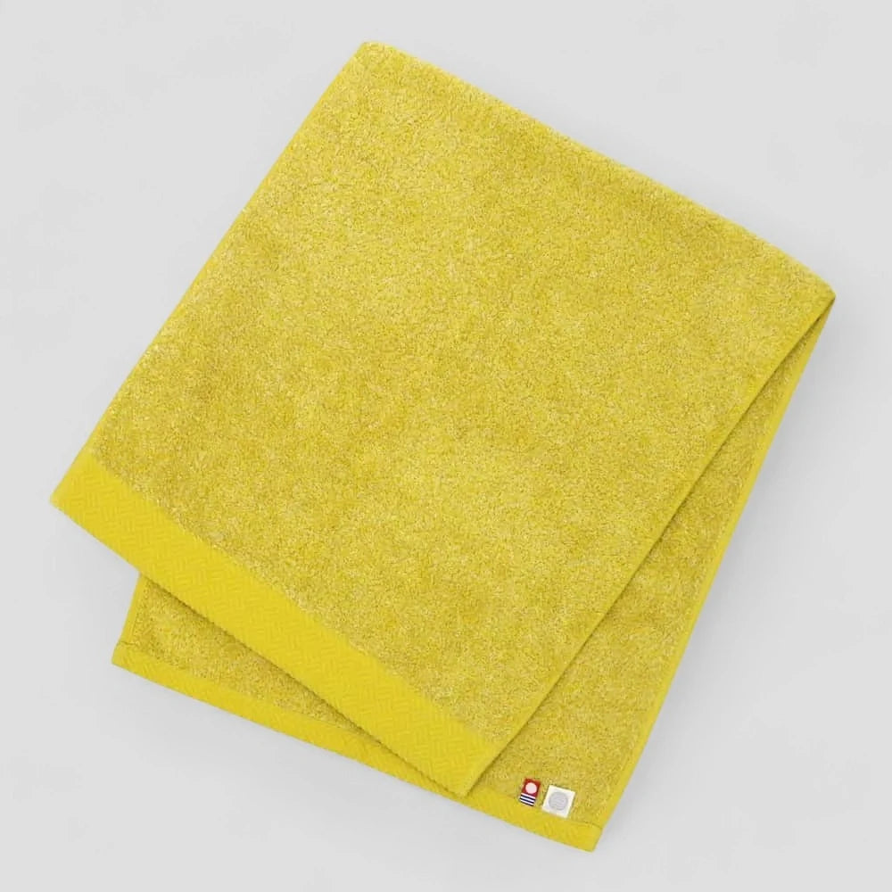 Folded yellow Imabari towel with light gray background.
