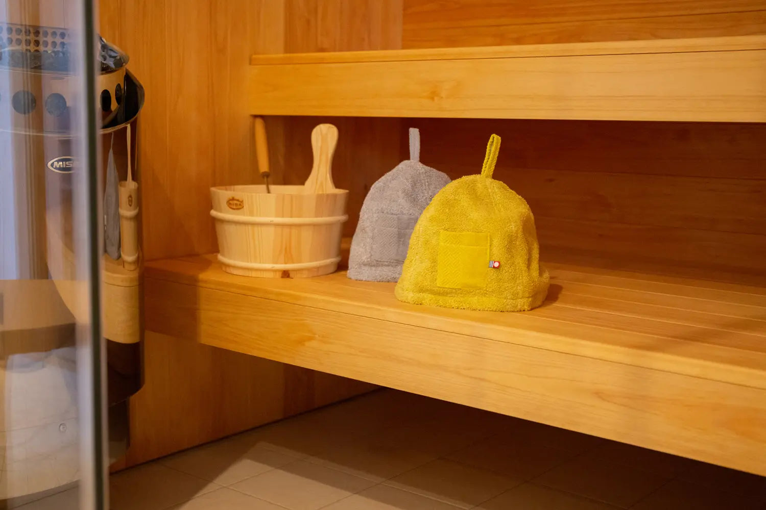 Yellow and gray sauna hats made from Imabari Towel are displayed on the sauna shelf.
