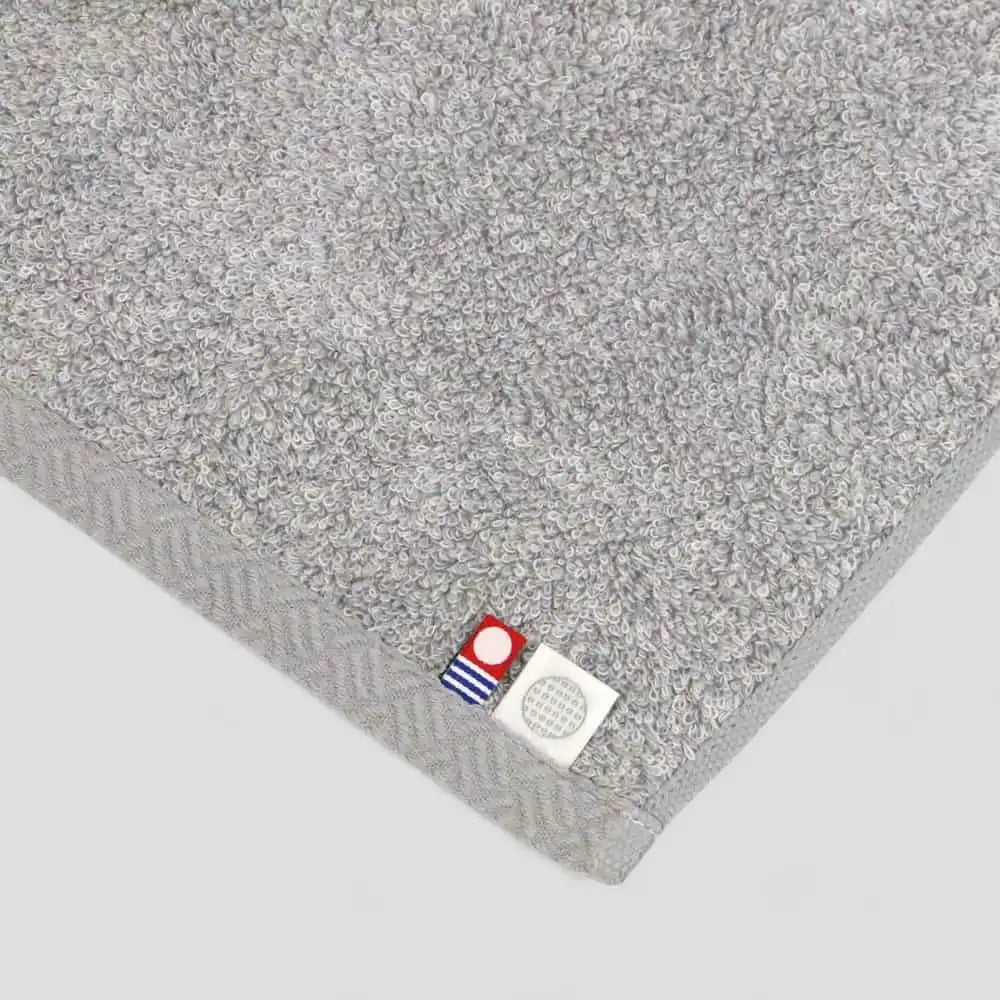 Close-up of a gray Imabari towel with label of Imabari towel brand and IORI brank mark.