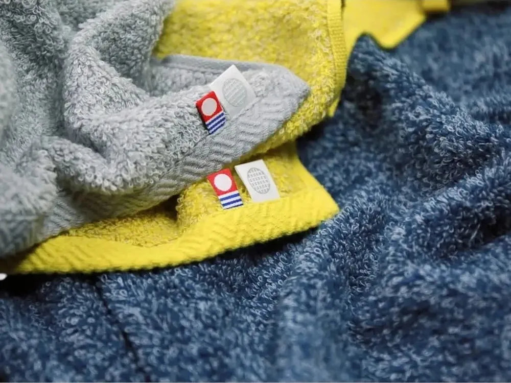 Close-up of colorful Imabari towels with labels of Imabari brand mark and IORI brand logo.
