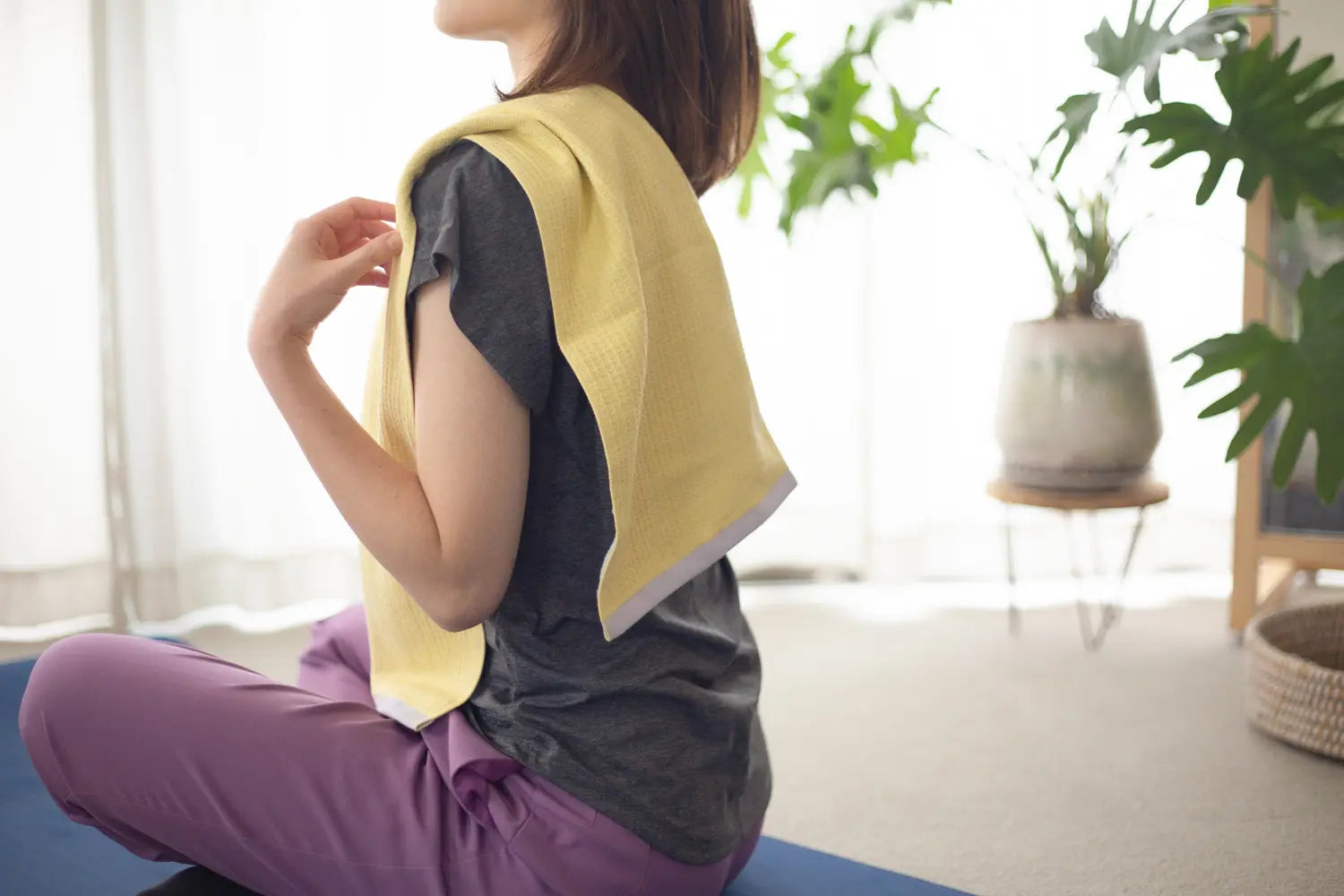 A woman with a sports towel over her shoulders after a yoga-exercise