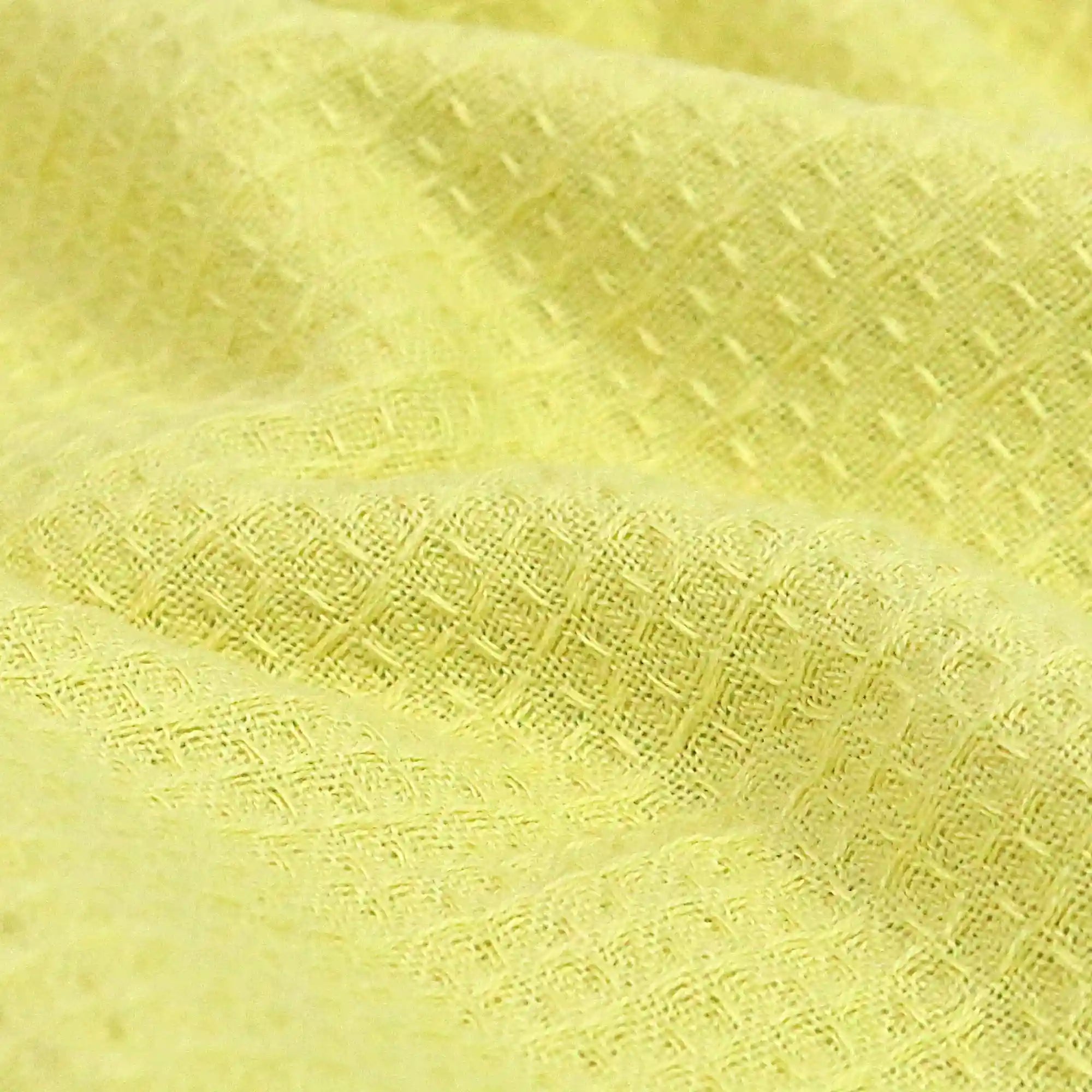 A close-up of the texture of a yellow waffle-weave Imabari towel for sports.