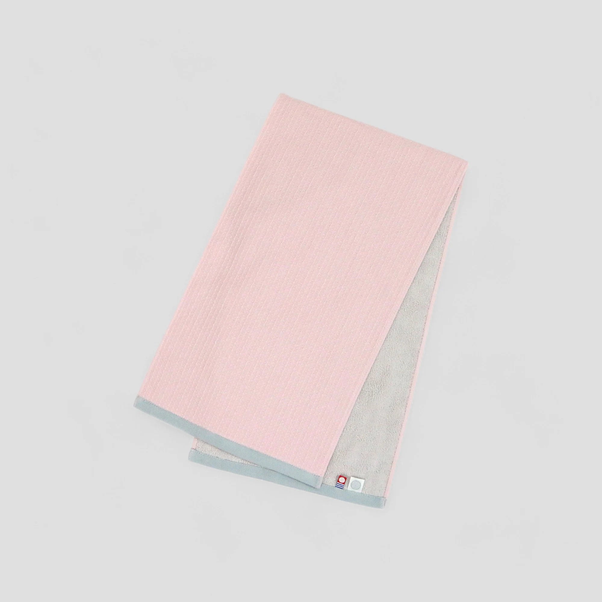 A folded pink Imabari towel with the brand label visible.