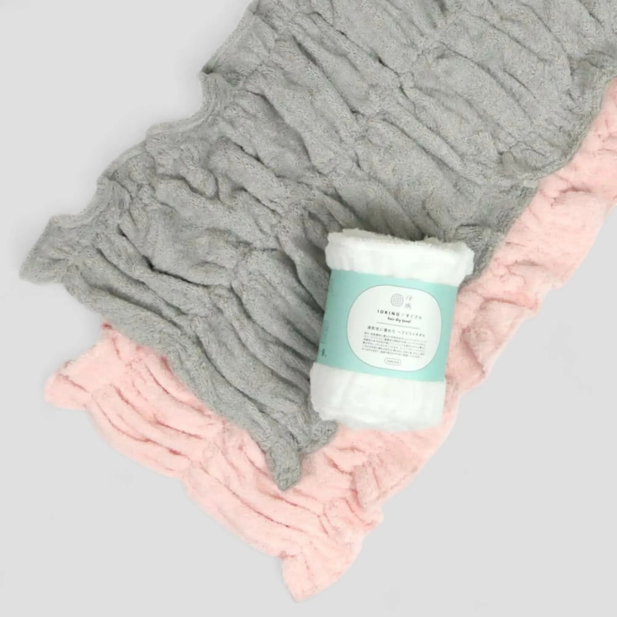 Gray, white and pink textured Imabari towel hair-dry-towel on a light gray background