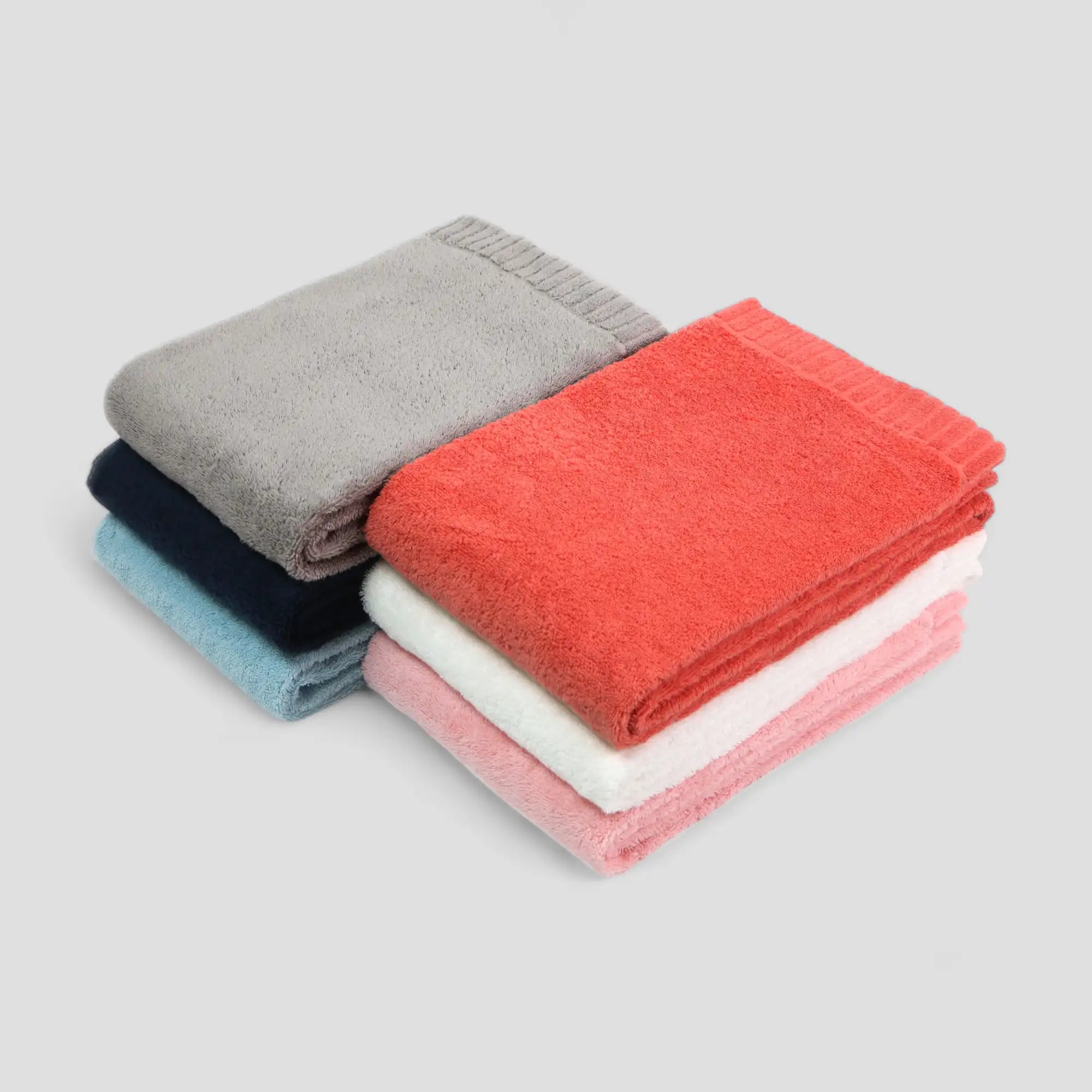 Stack of folded Imabari towels in various colors on a light gray background