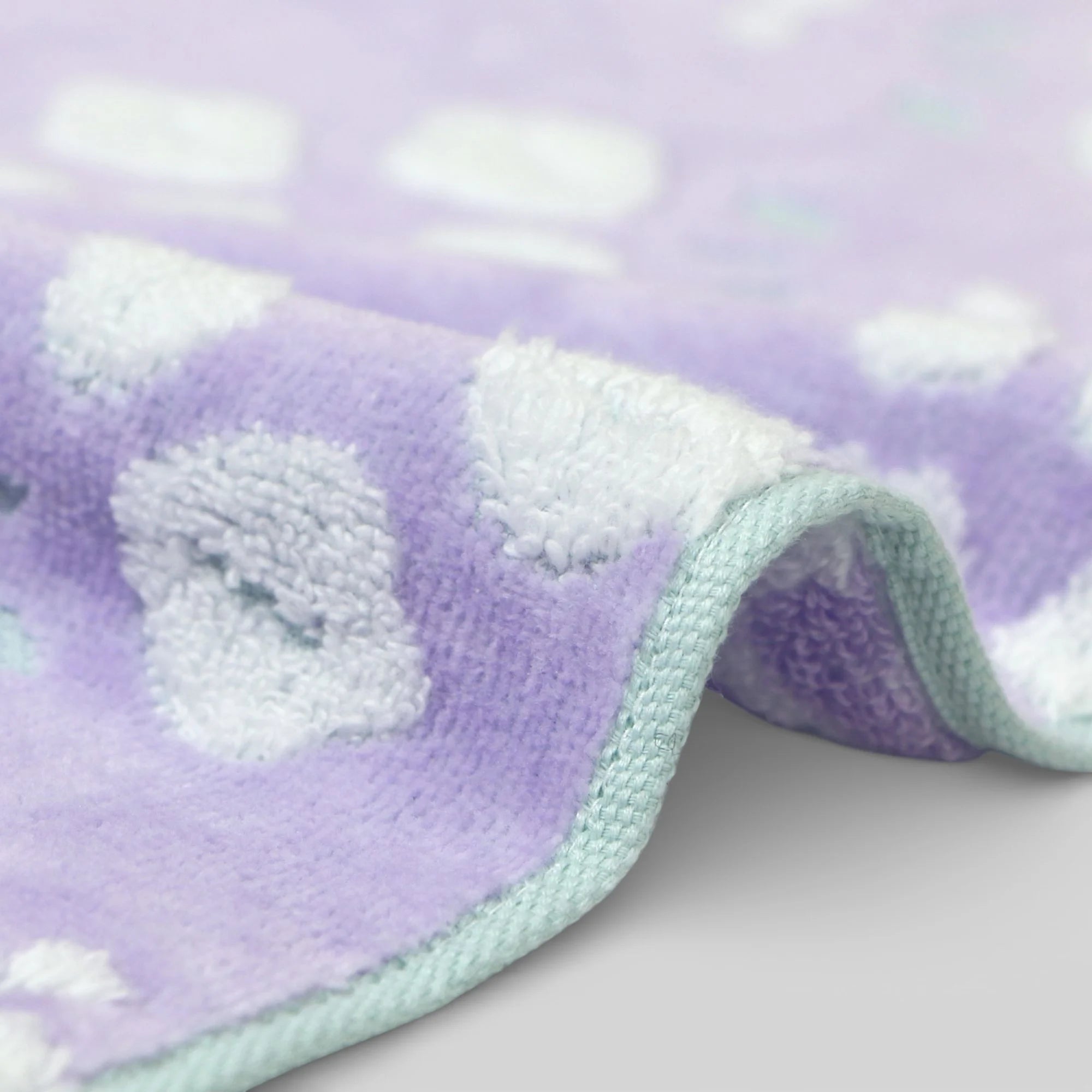 Close-up of a textured purple and white fabric with a floral pattern Imabari towel on a light background.