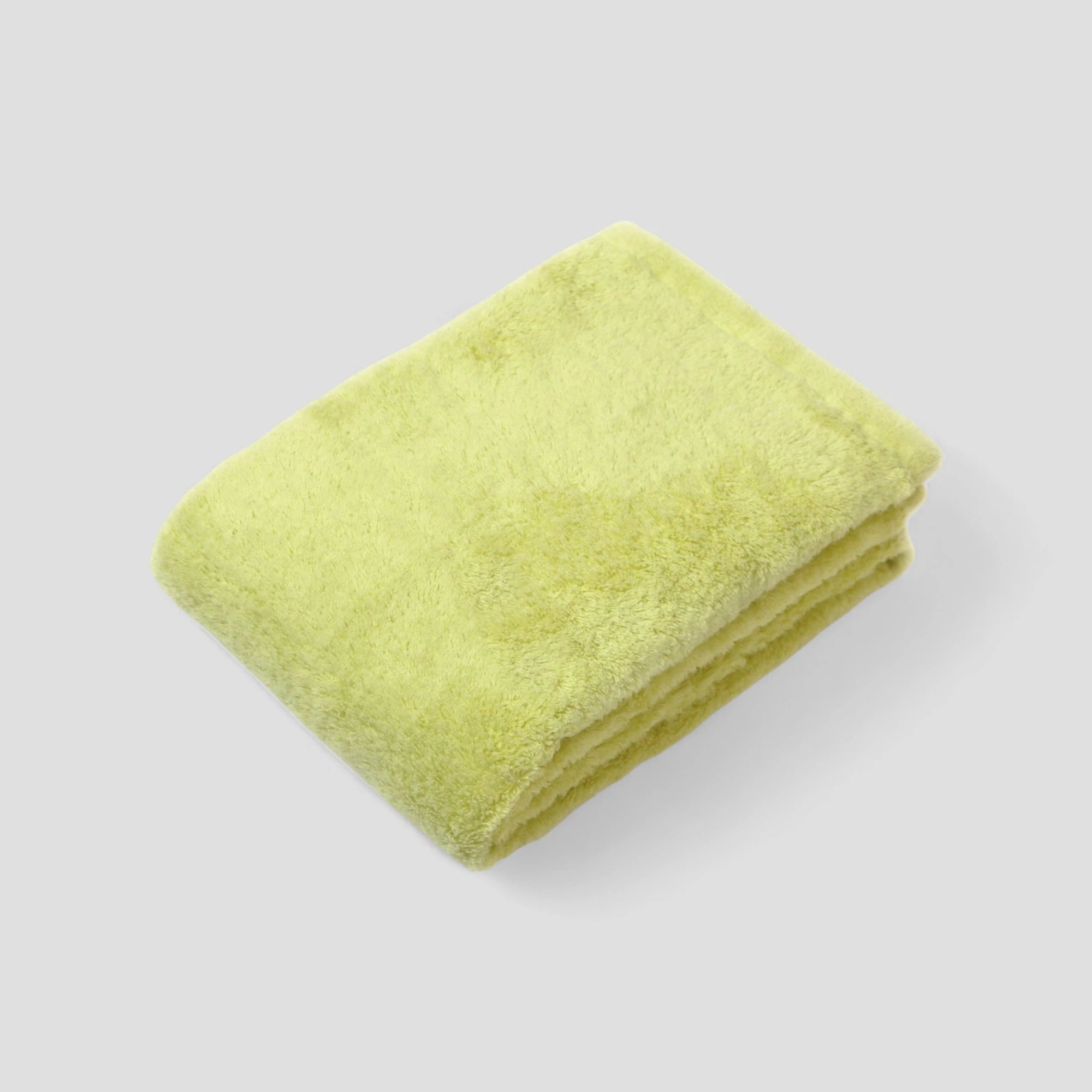 Folded green Imabari towel on a light gray background