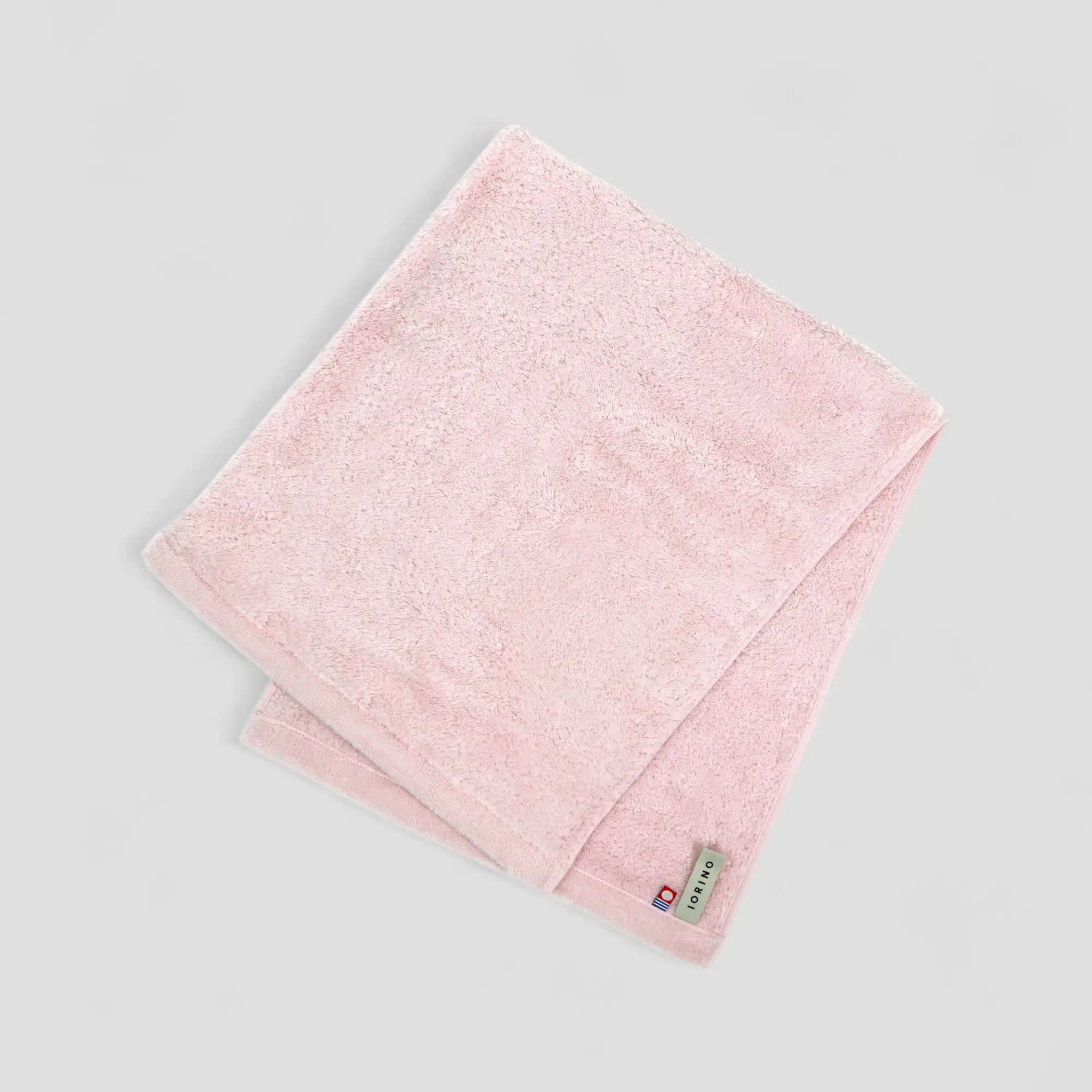 Pink Imabari towel with a brand label on a light gray background