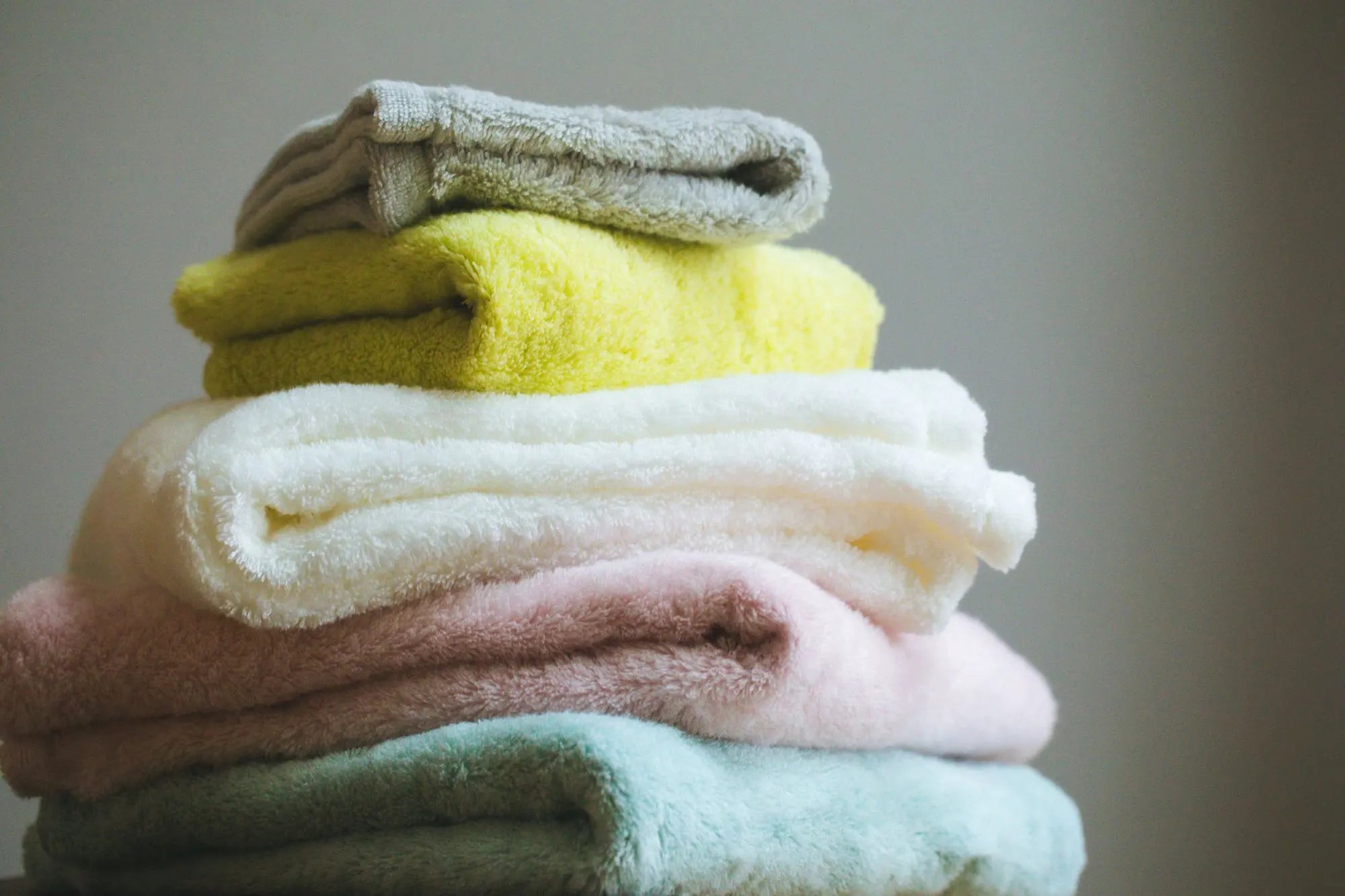 Stack of folded colorful Imabari towels on a neutral background