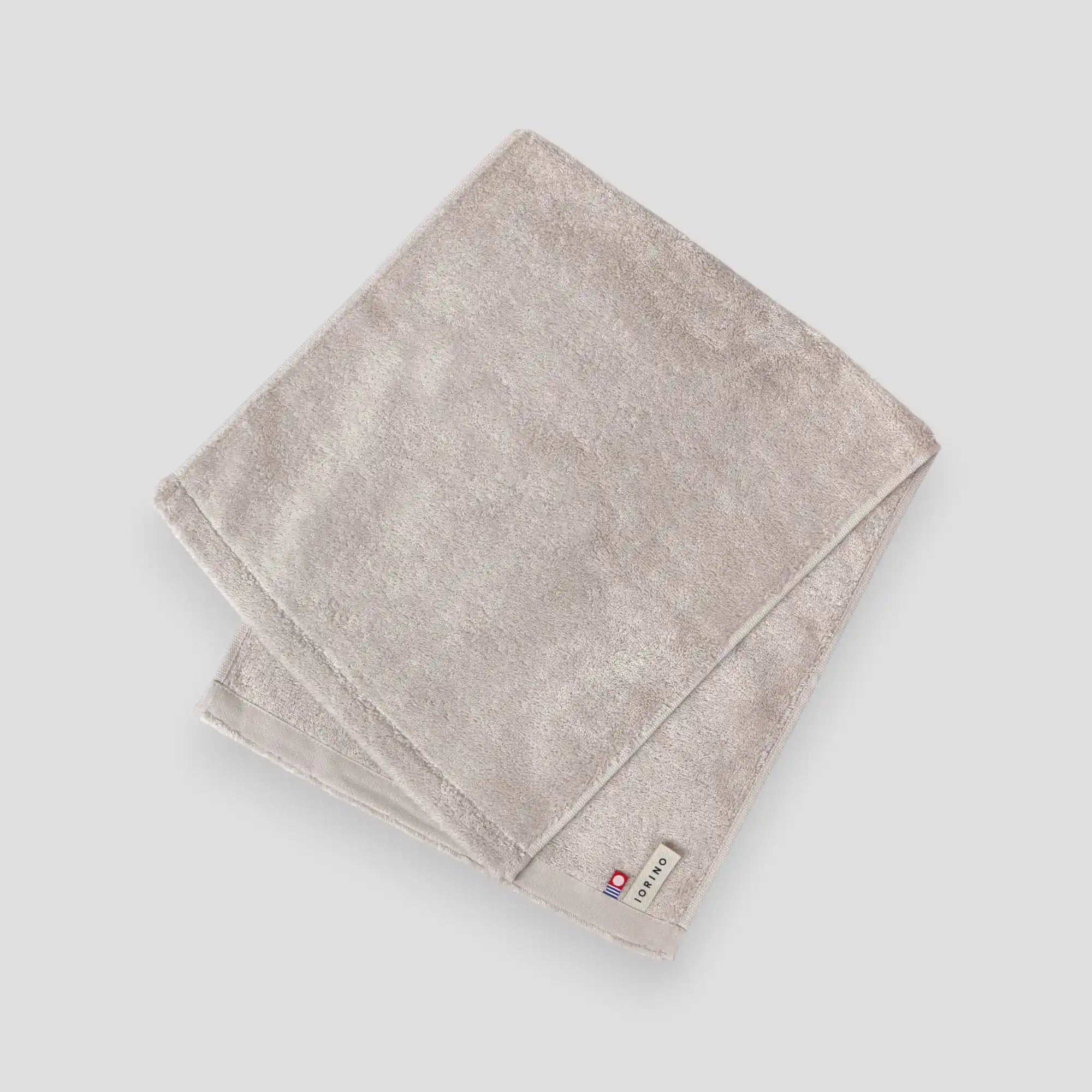 Folded beige Imabari towel on a light gray background