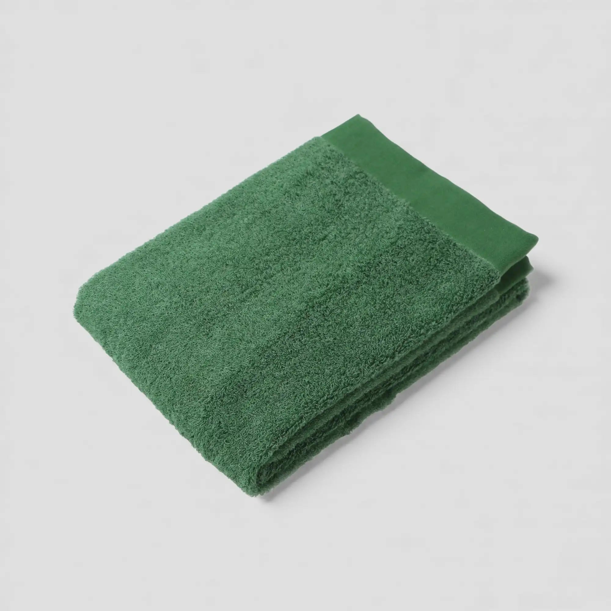 Folded green Imabari towel on a light gray background