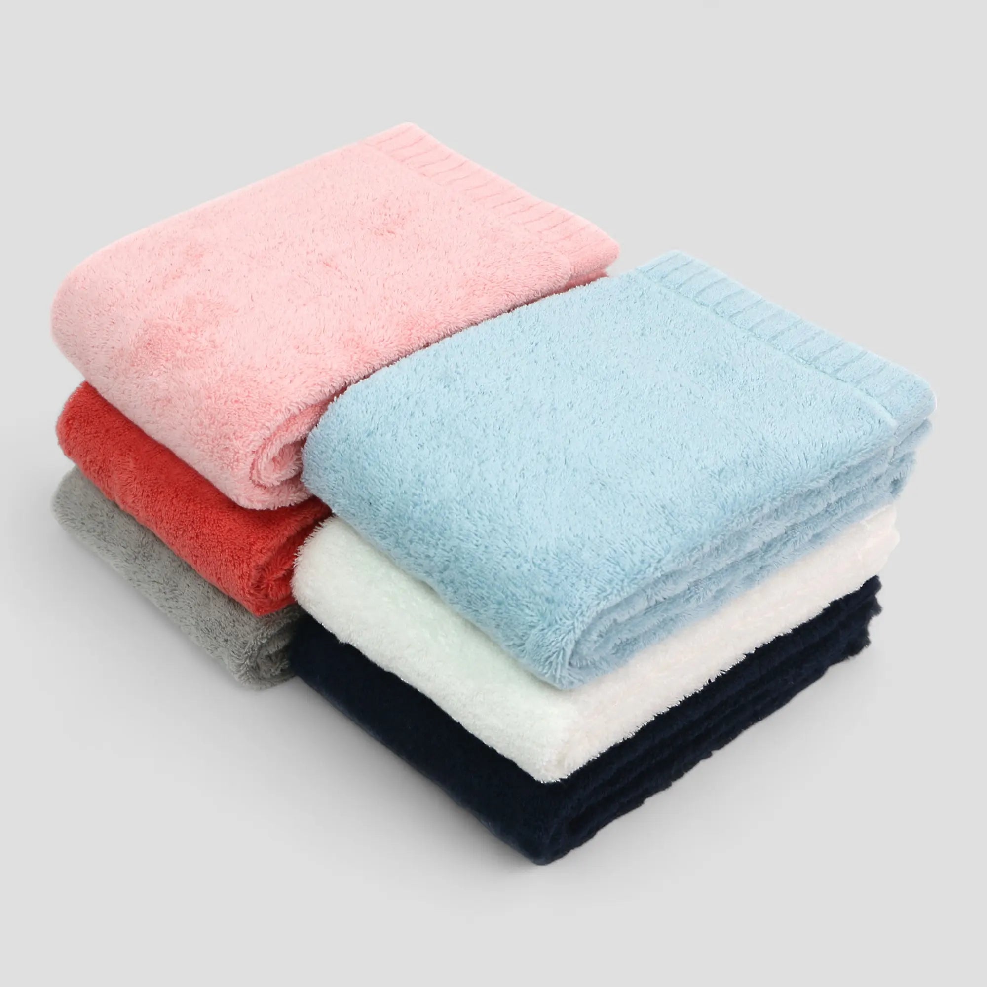Stack of folded Imabari towels in various colors on a light gray background