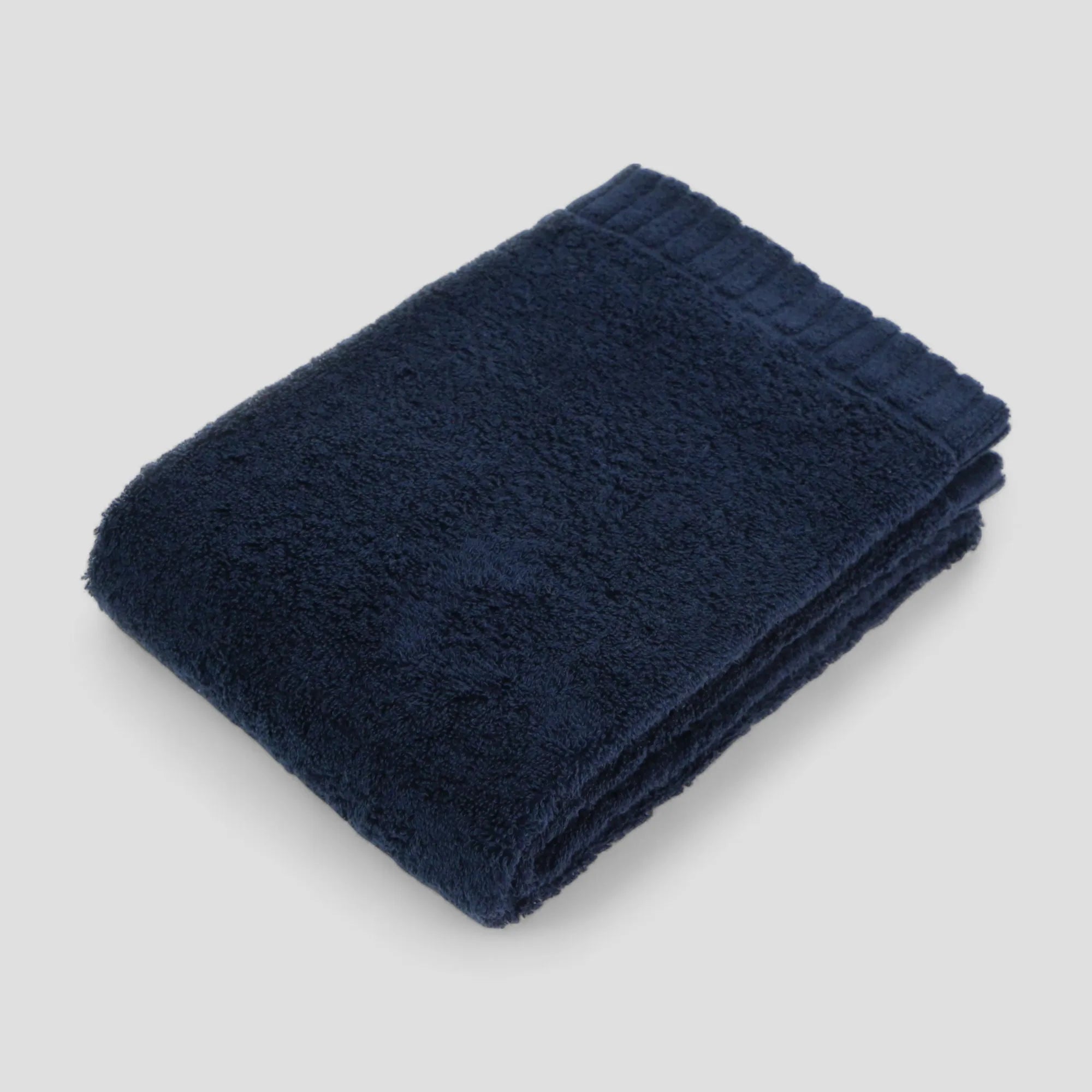 Folded navy blue Imabari towel on a light gray background