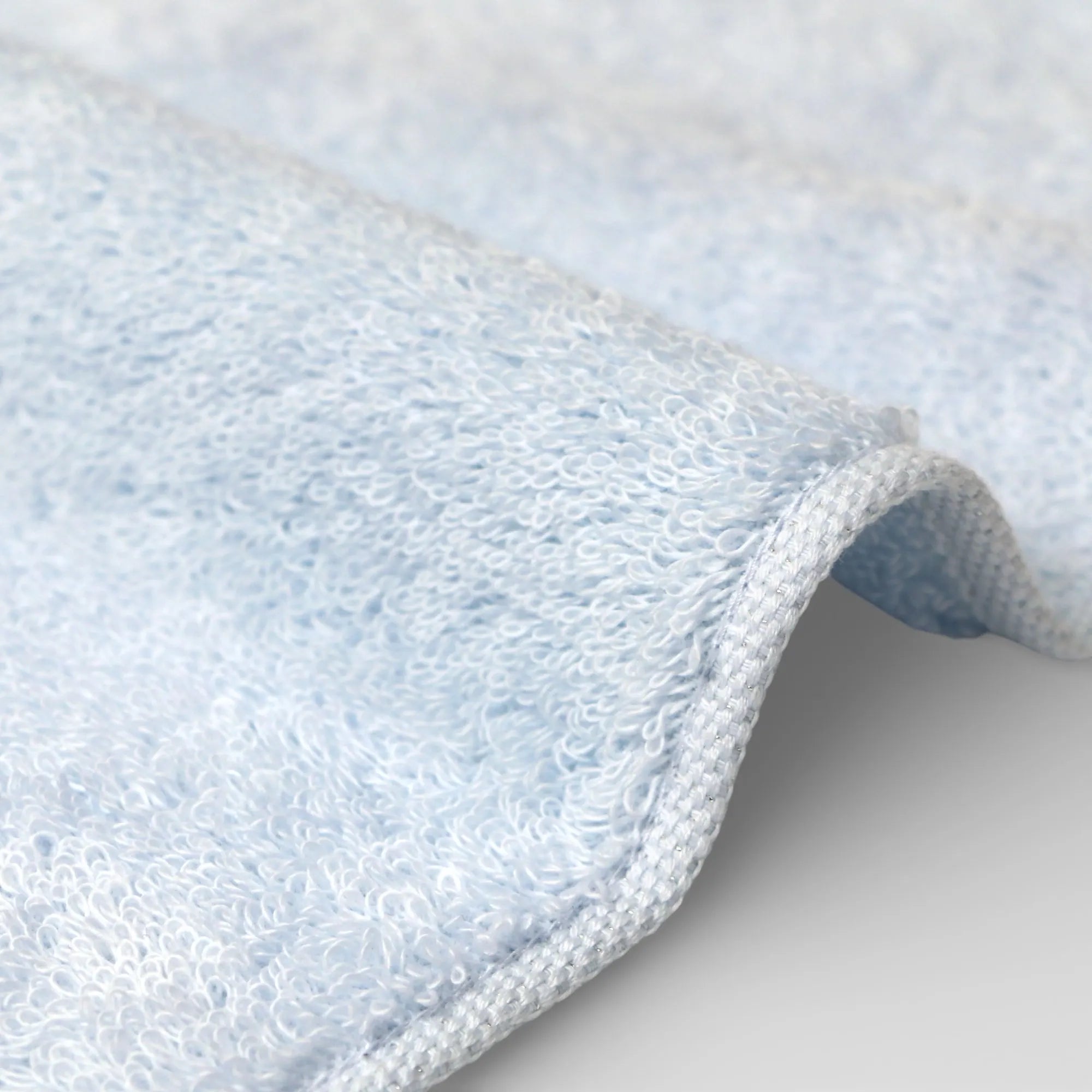 Close-up of a textured blue Imabari towel fabric on a light gray background