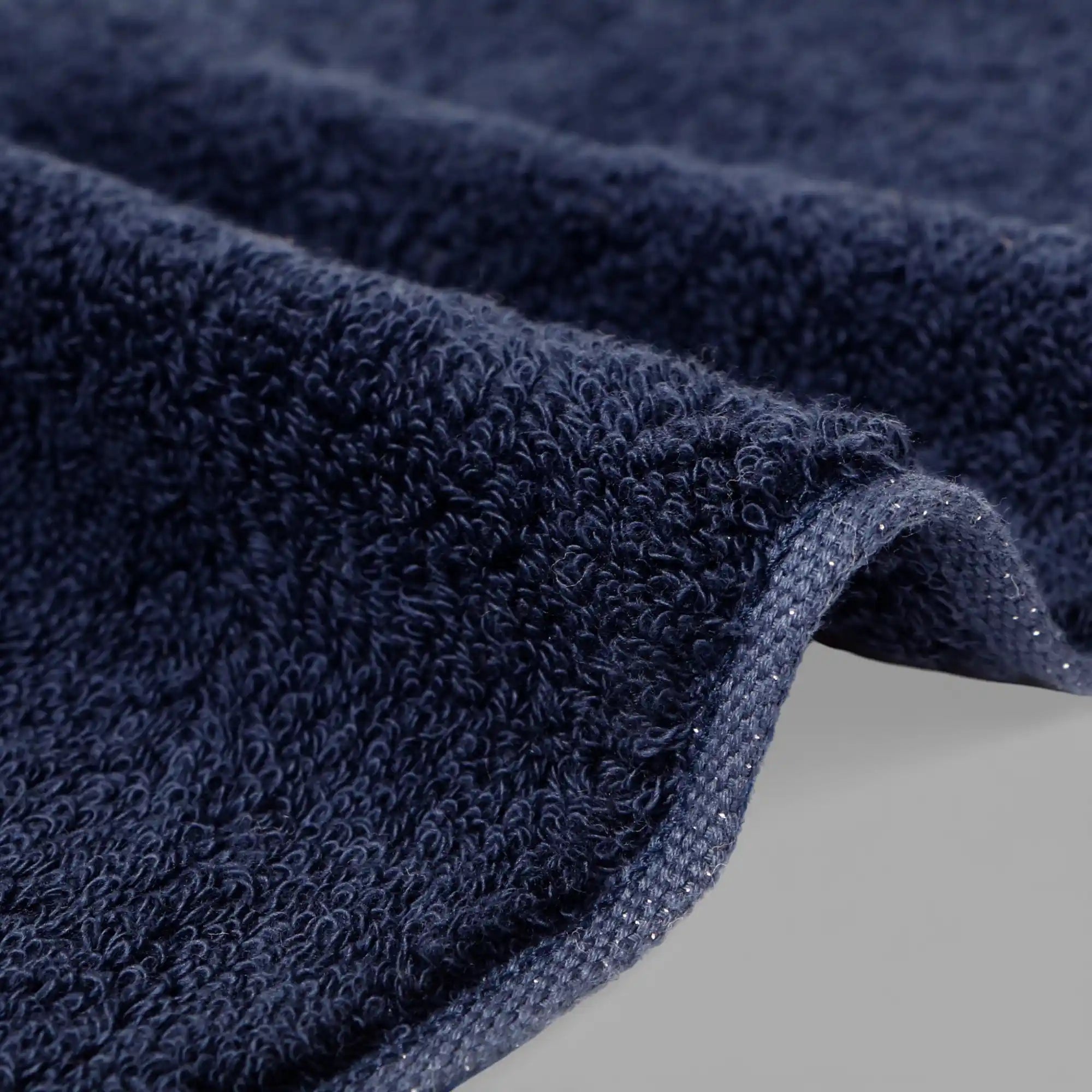 Close-up of a navy blue Imabari towel with textured surface on a light gray background