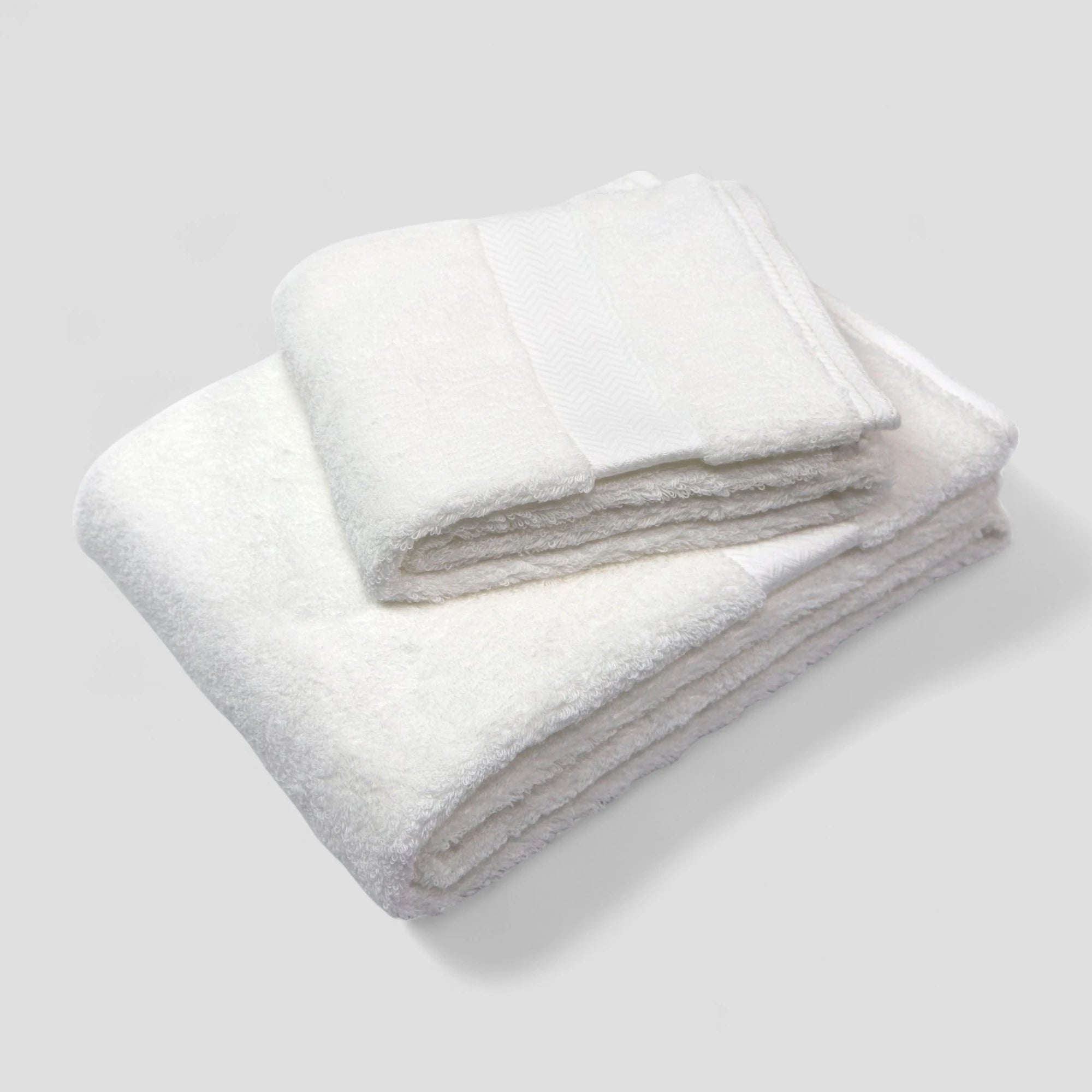 Folded white Imabari towels on a light gray background