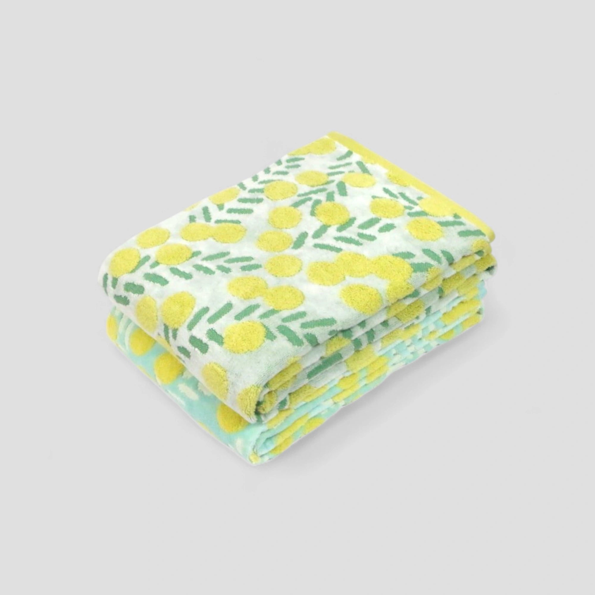Stack of folded Imabari towels with yellow floral pattern in the blue and white fabric on a light gray background