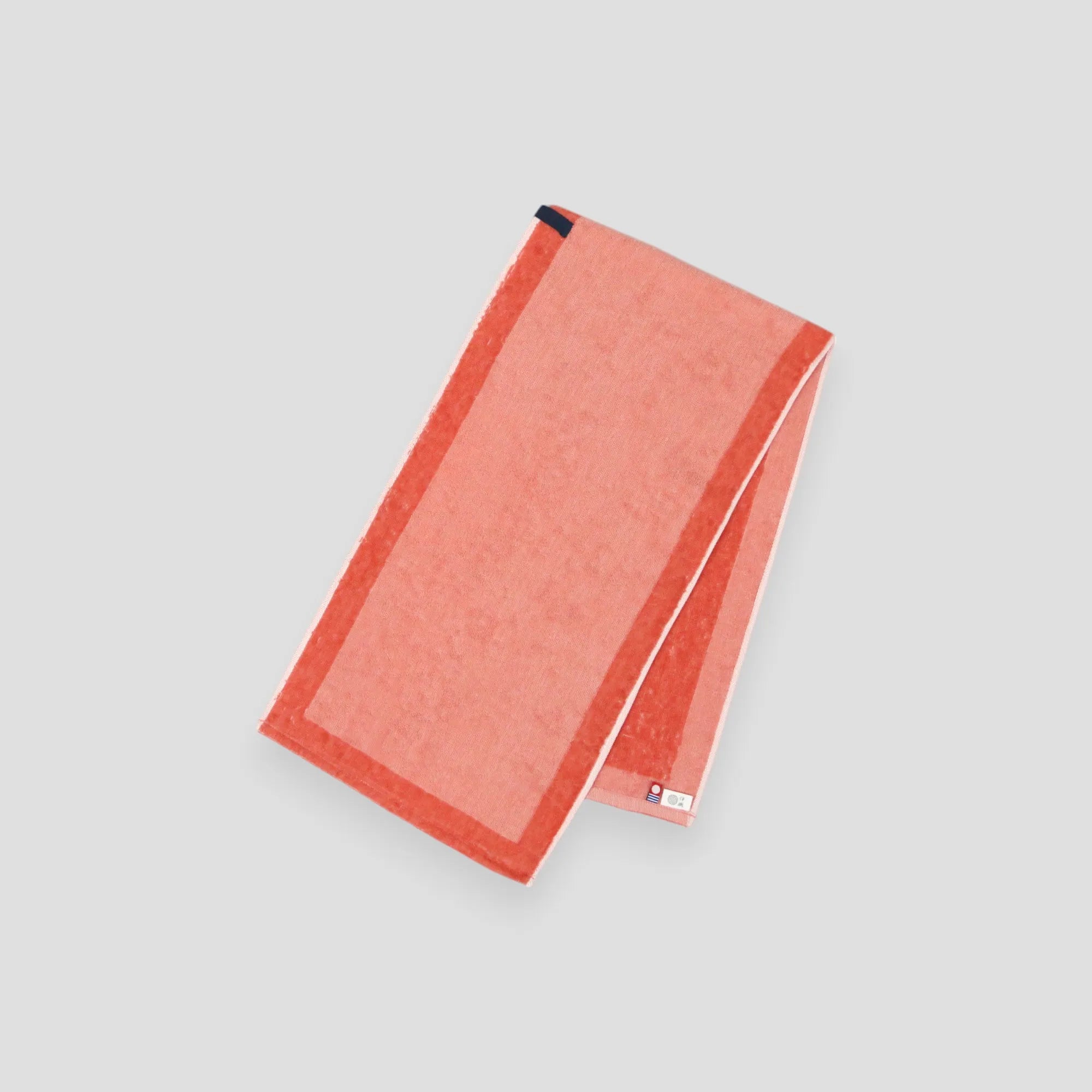 A folded orange Imabari towel, showing the brand label and a hanging loop