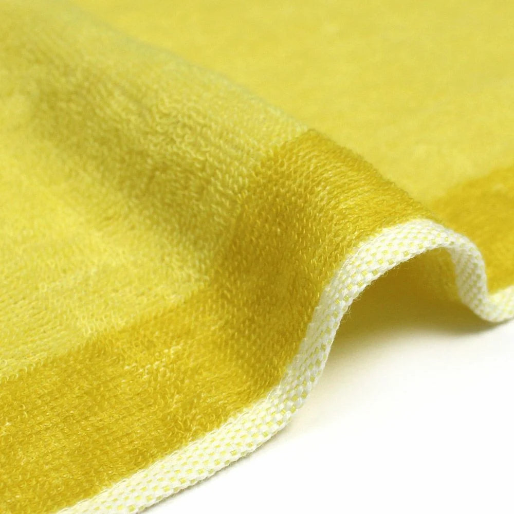 A close-up of the texture and side of a reversible yellow Imabari towel